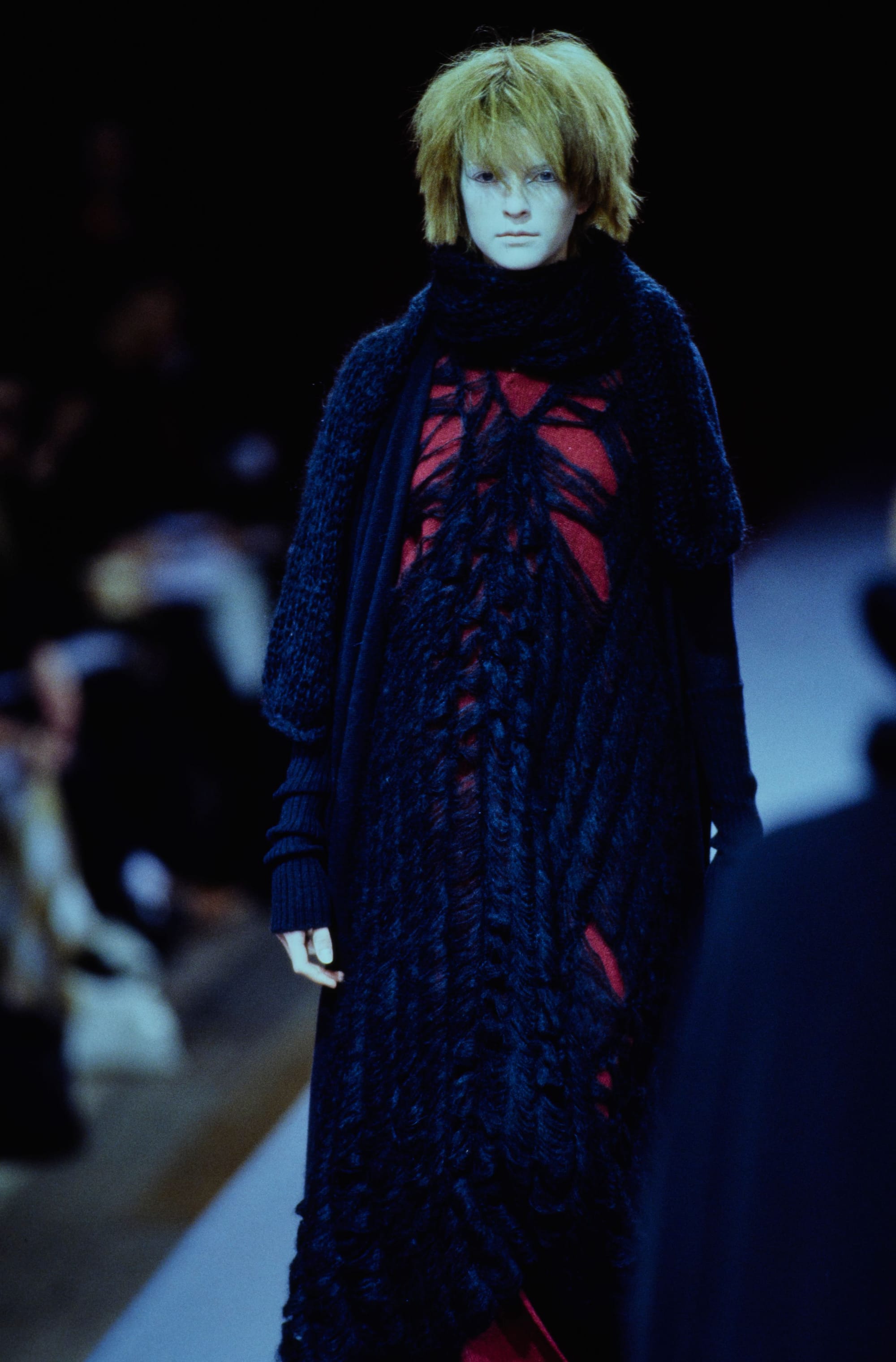 Yohji Yamamoto Fall 1995 detail 39: Dark shaggy coat with a red garment showing through its openwork front.
