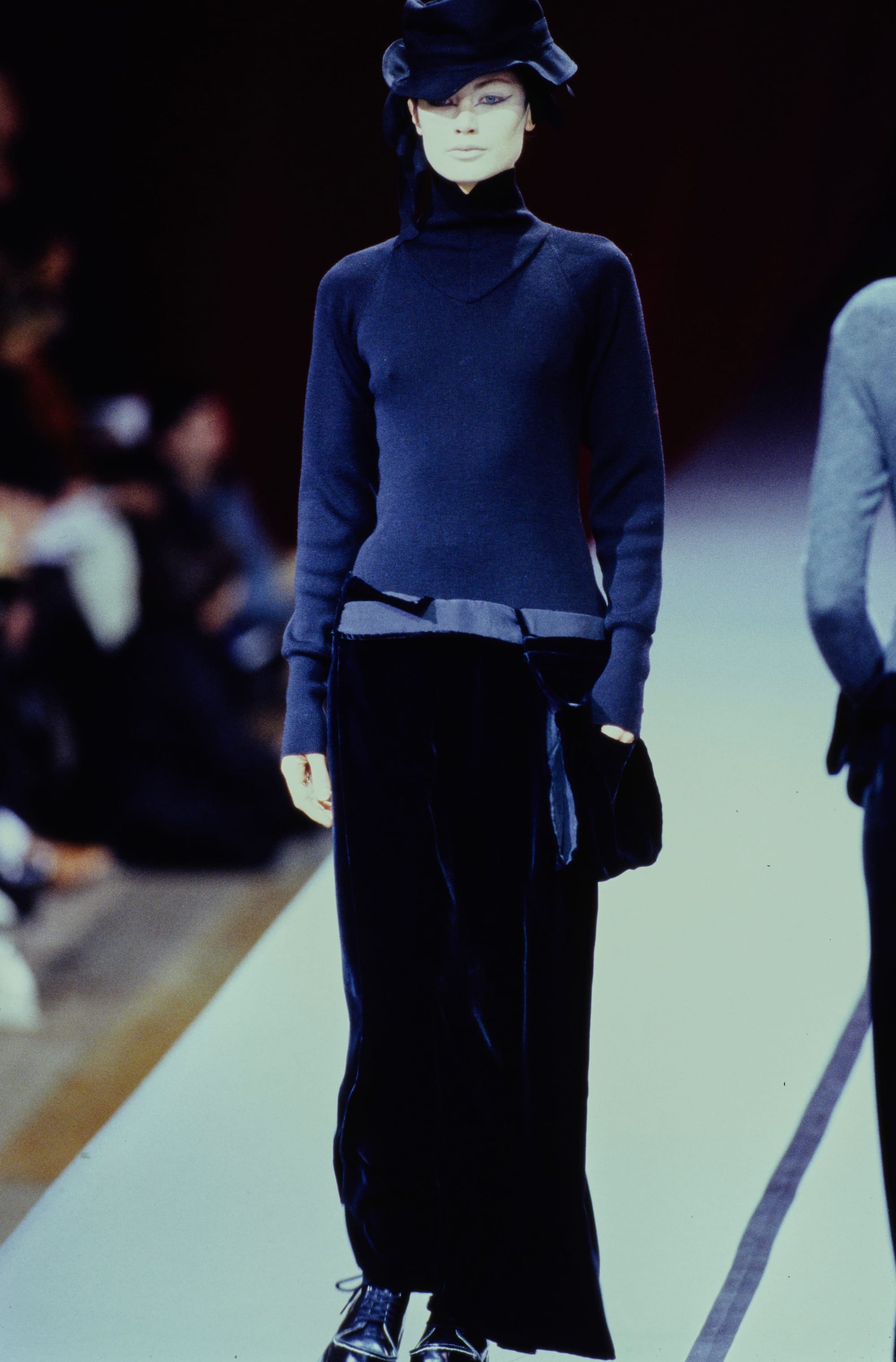 Yohji Yamamoto Fall 1995 detail 45: Dark navy turtleneck with a pale band at the waist above wide black trousers.