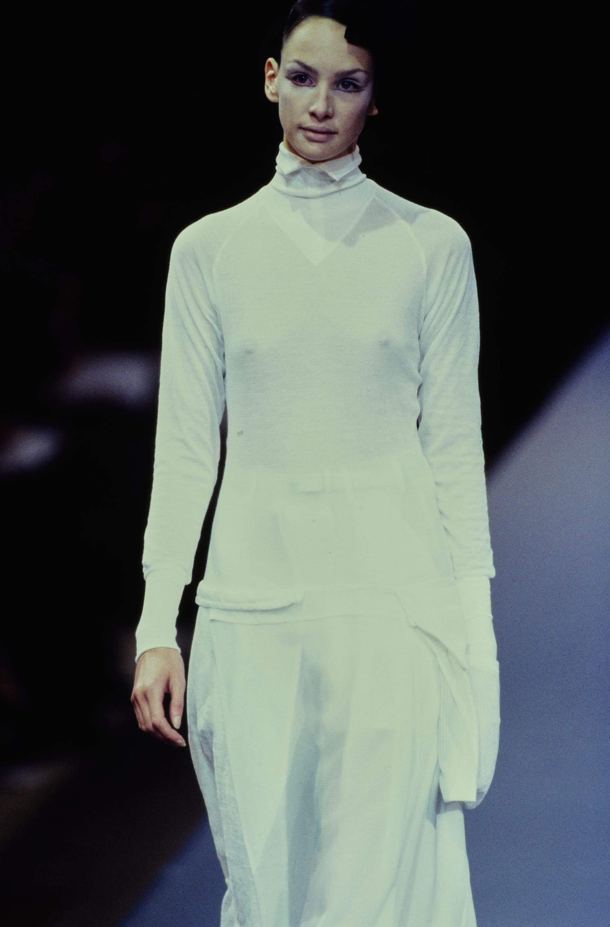 Yohji Yamamoto Fall 1995 detail 47: Closer view of a white high-neck long-sleeved top and soft white draped skirt.