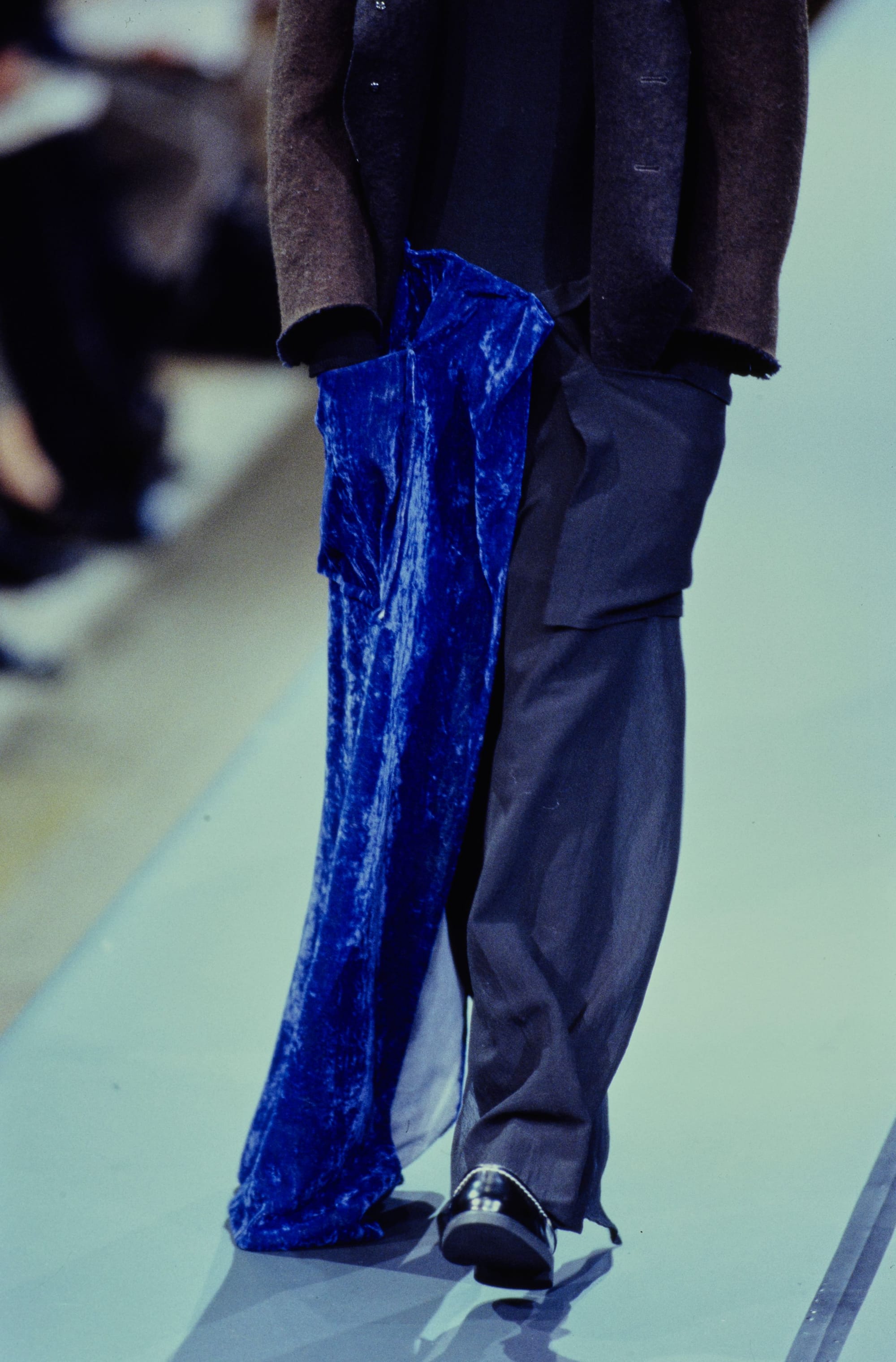Yohji Yamamoto Fall 1995 detail 50: Close view of a cobalt-blue velvet panel hanging beside dark wide trousers.