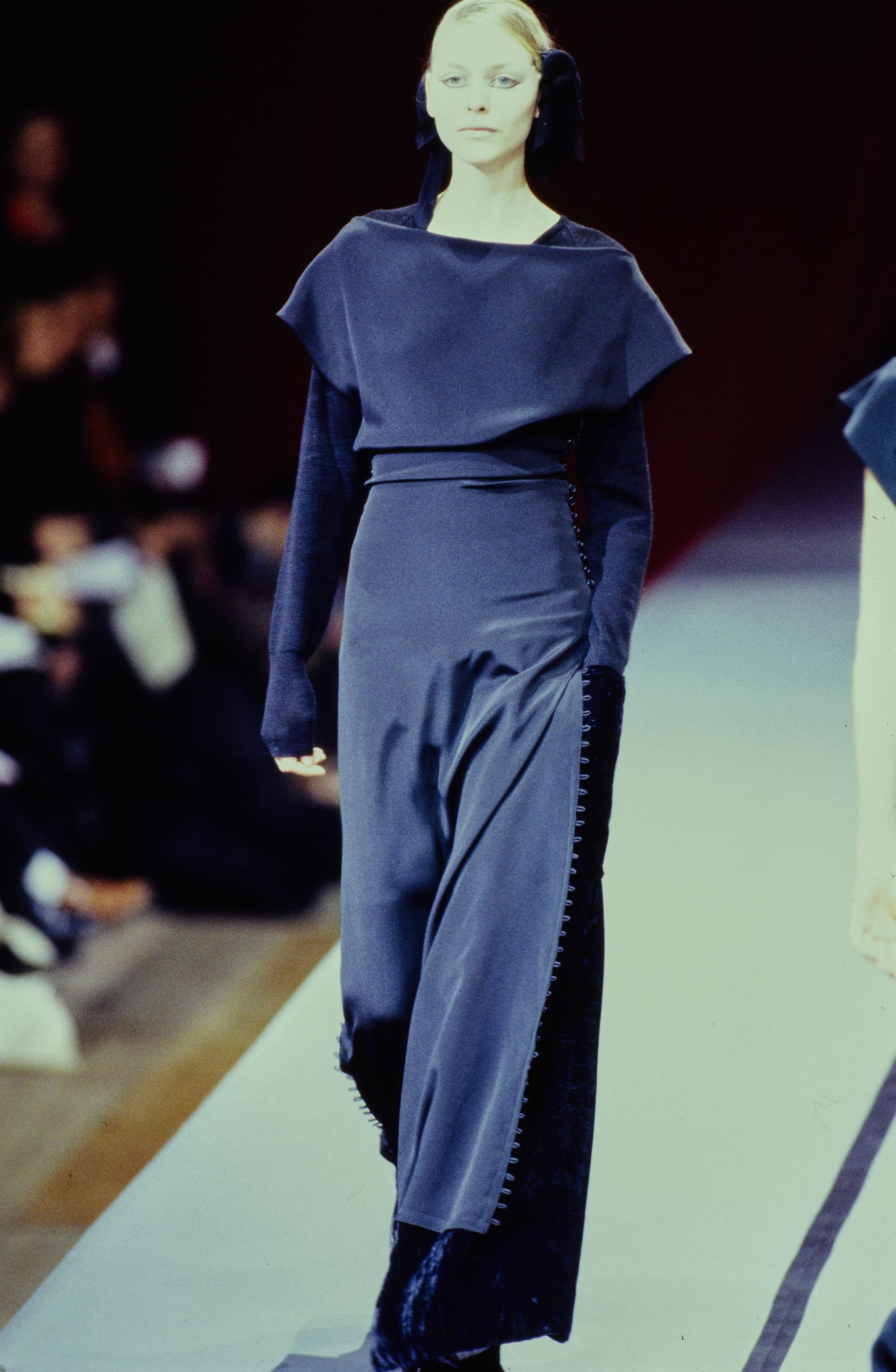 Yohji Yamamoto Fall 1995 detail 53: Slate-blue dress with a wide shoulder flap and a line of buttons down one side.