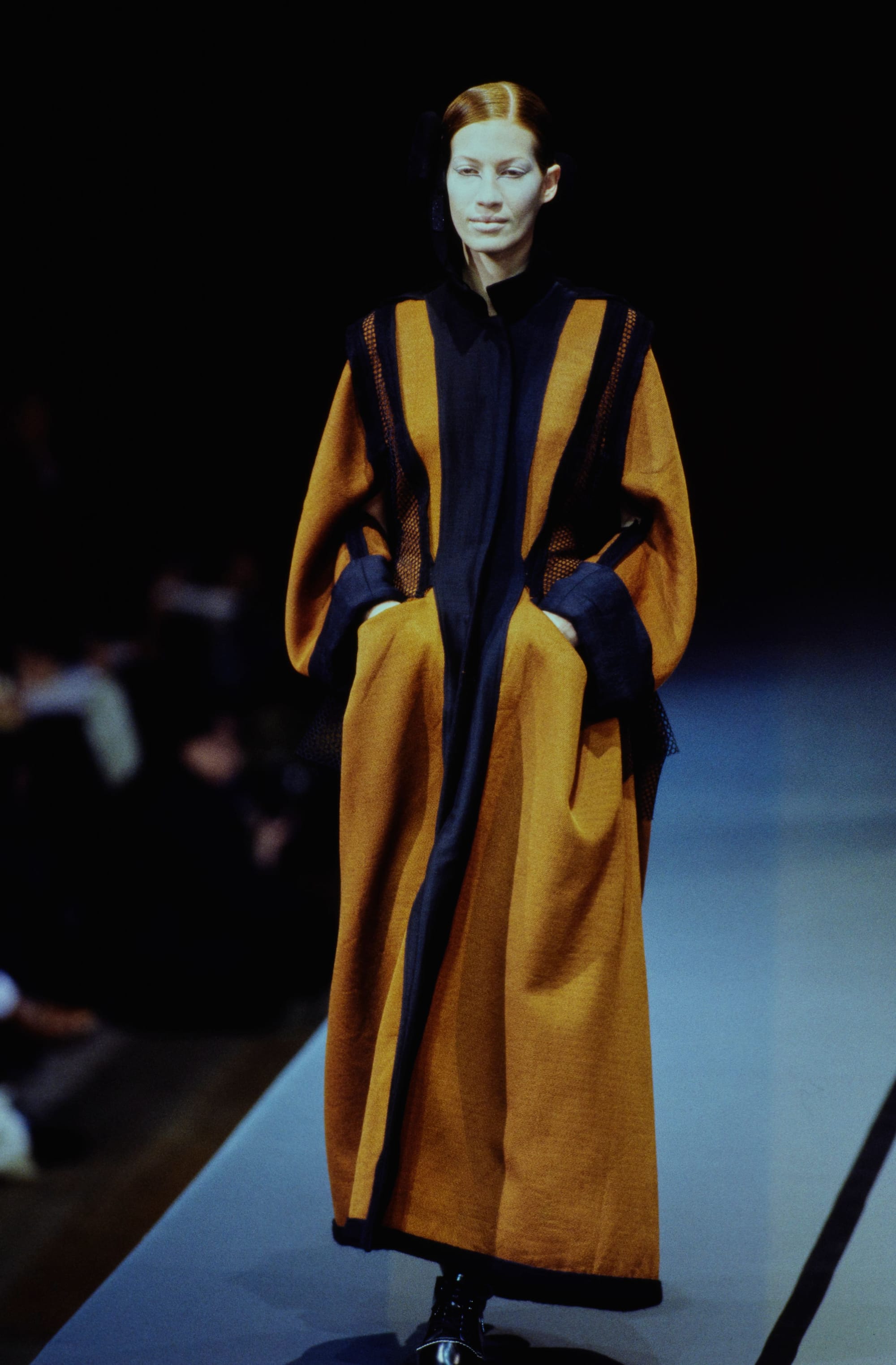 Yohji Yamamoto Fall 1995 detail 61: Front view of a long mustard coat with navy center strip and voluminous sleeves.