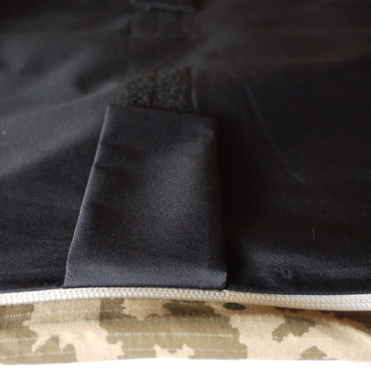 Bonded black fabric, hook-and-loop fastening and camouflage hem detail on the Griffin Technical Bearskin jacket.