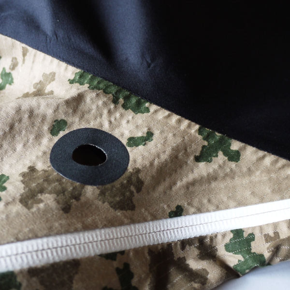 Detail of a black ventilation eyelet and white waterproof-taped zip on the Griffin Technical Bearskin jacket.