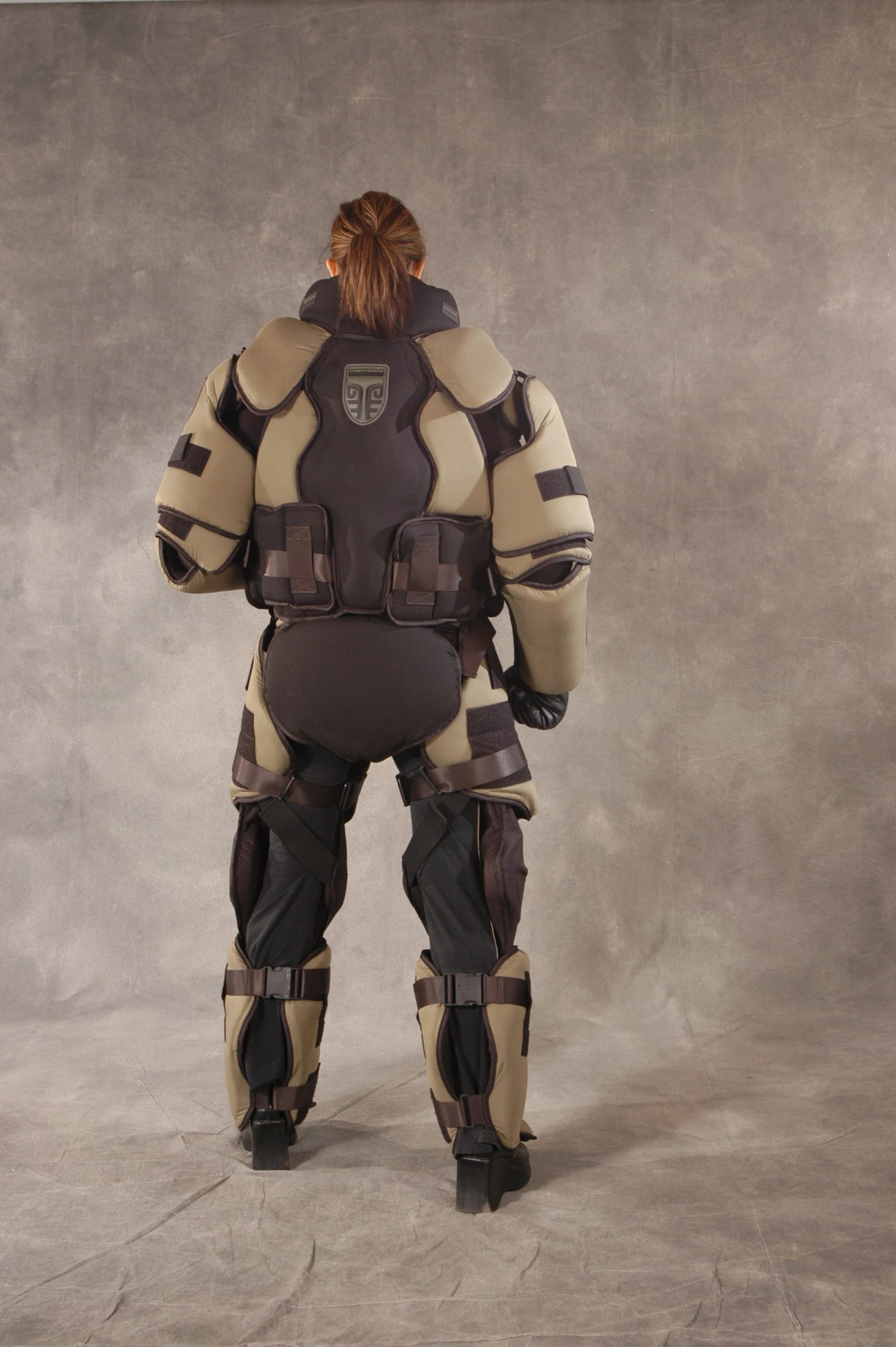 Rear view of the khaki and black Mawashi T-RED training suit, showing segmented back, arm, hip, and leg protection.