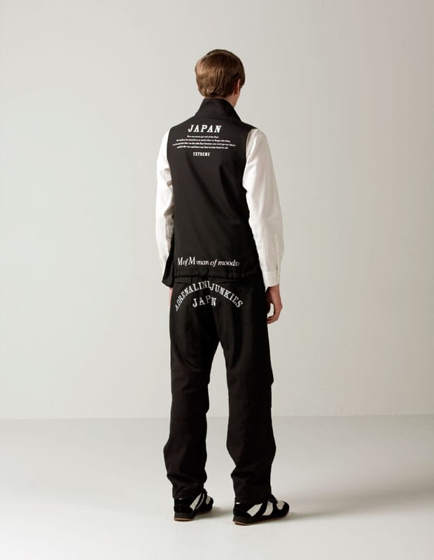 Rear view of a black Man of Moods utility vest and trousers printed JAPAN, MofM man of moods, and ADRENALIN JUNKIES JAPN.