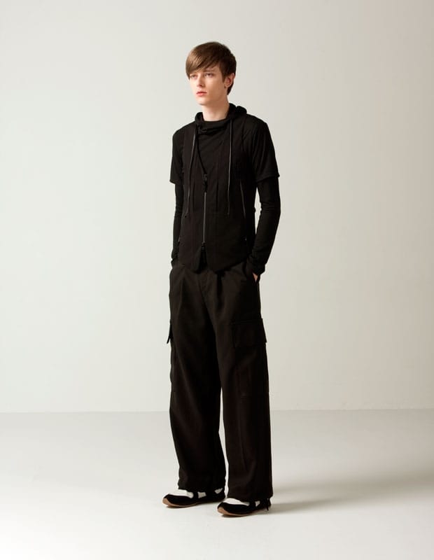 Male model in layered black Man of Moods hooded tops with wide black cargo trousers.