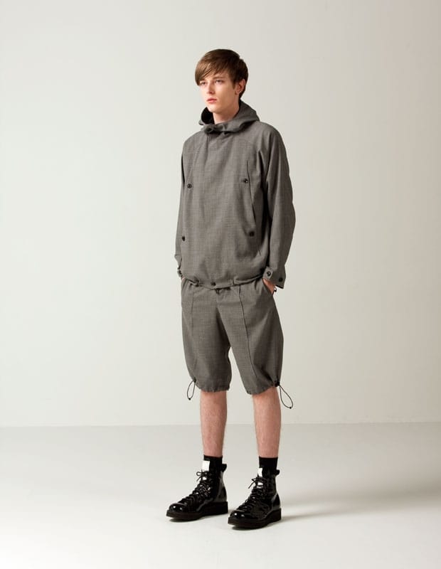 Male model in a grey Man of Moods hooded pullover and matching knee-length drawcord shorts.
