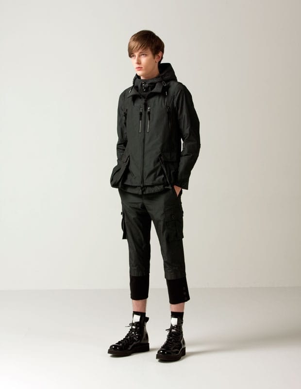 Full-length Man of Moods look with a black hooded technical jacket, cropped cargo trousers, and lace-up boots.