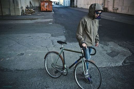 Model wearing the Nike ACG Sayagata Kimono Jacket beside a fixed-gear bicycle.