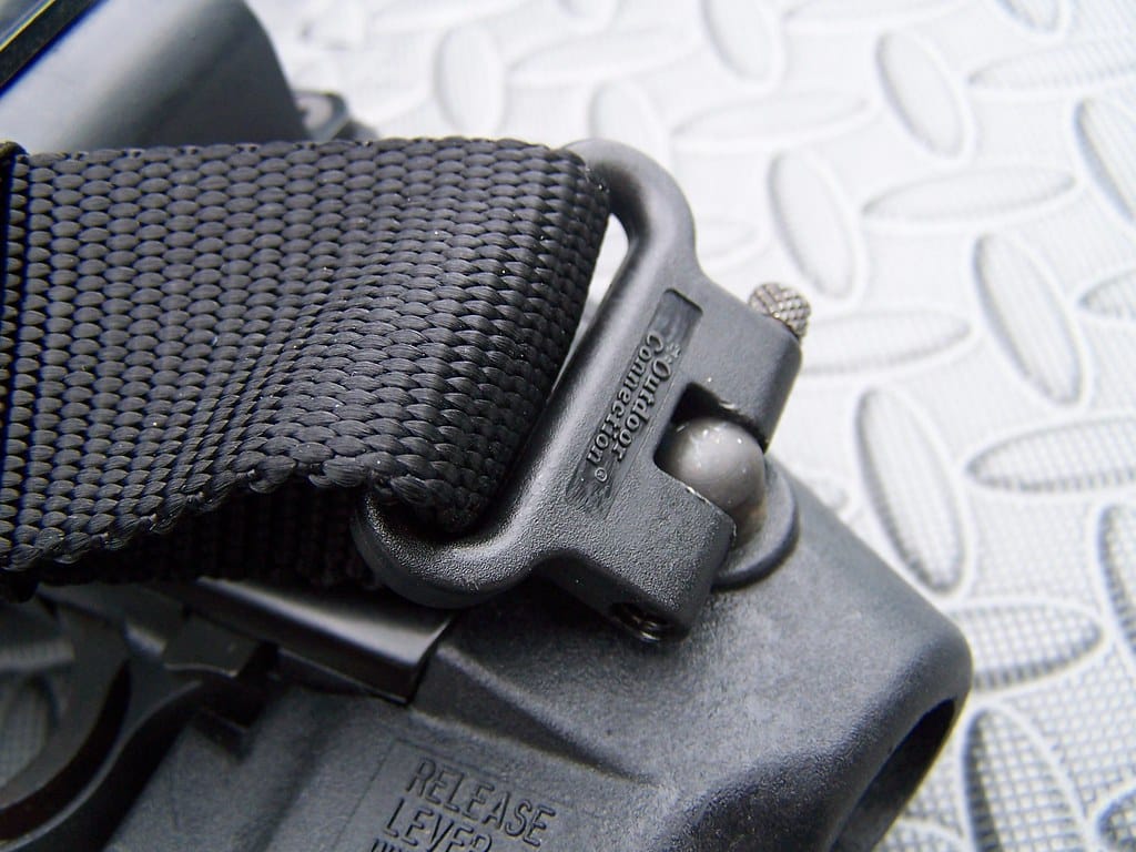 Close-up of the black sling webbing and GrovTec swivel mounted to the Mossberg 500 factory pistol grip.