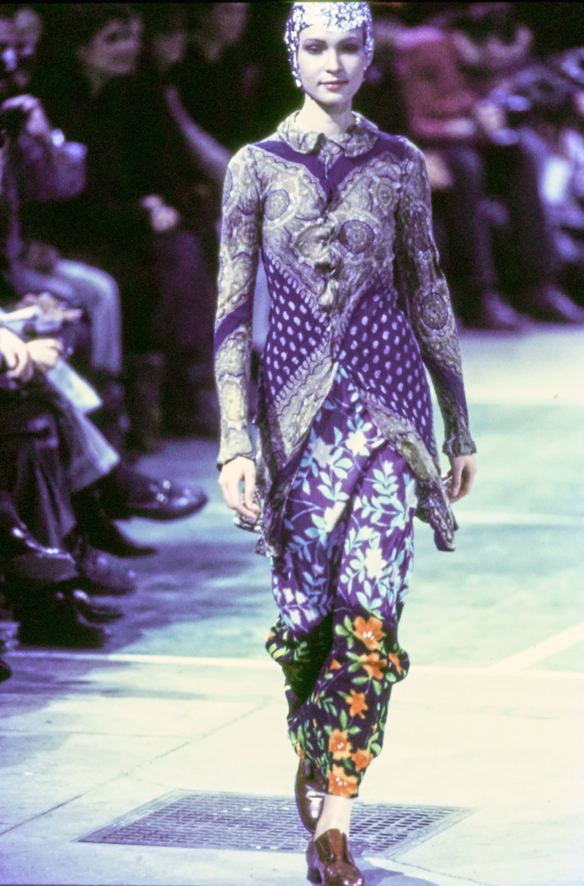 Comme des Garçons Fall 1993 Ready-to-Wear runway look 67: purple-and-green patterned dress over floral trousers.