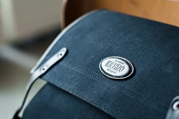Close-up of the oval KICHIZO badge on the black canvas top flap.
