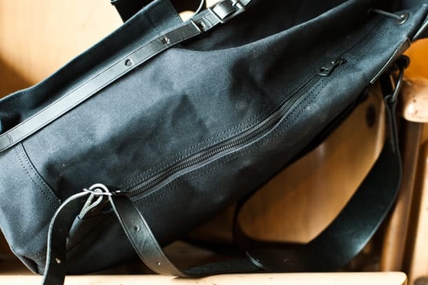 Side zipper and leather straps on the black KICHIZO canvas rucksack.