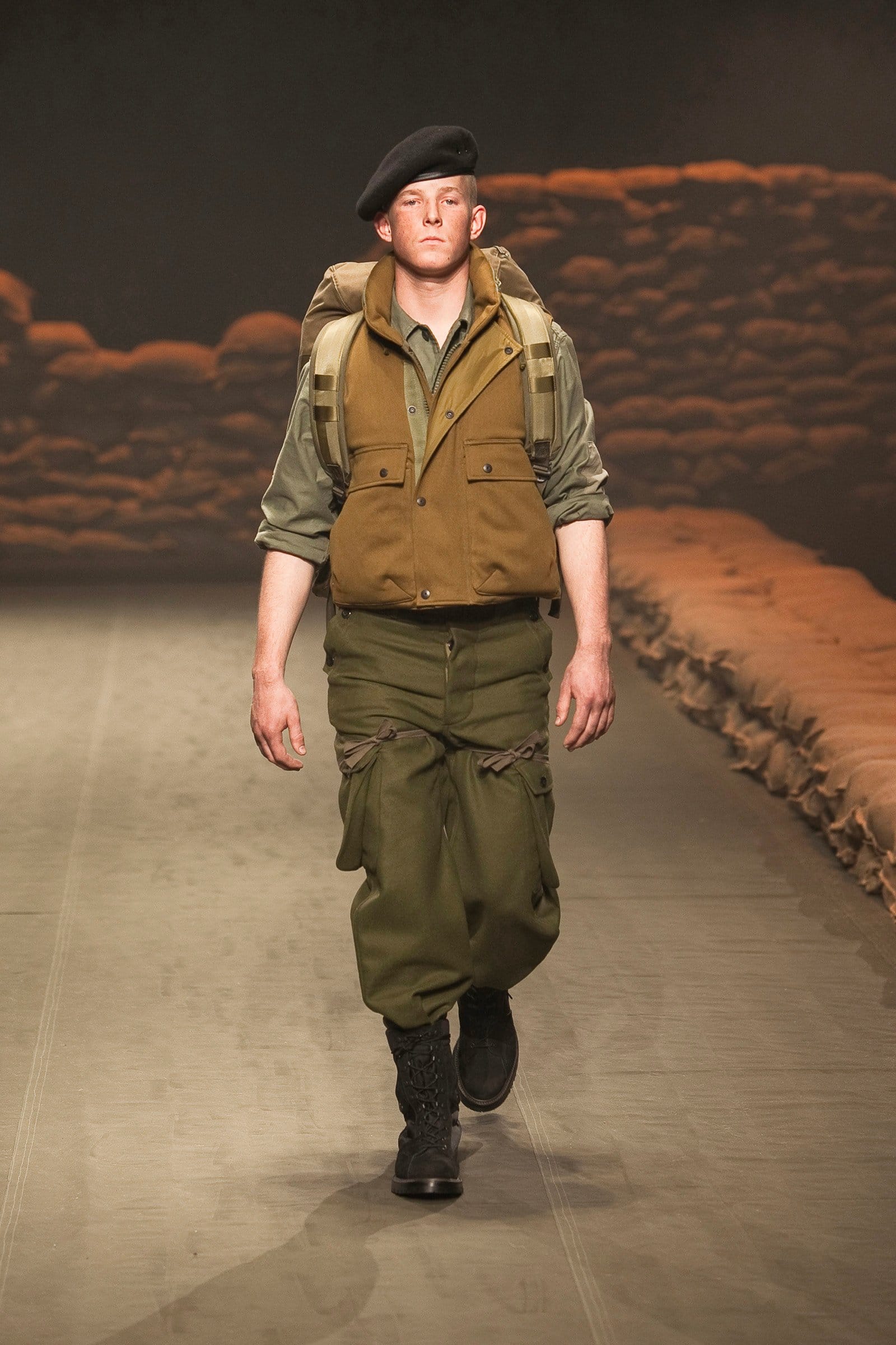 N.Hoolywood Autumn/Winter 2010–11 runway look 2: olive utility vest over a field shirt with loose cargo trousers and a black beret.