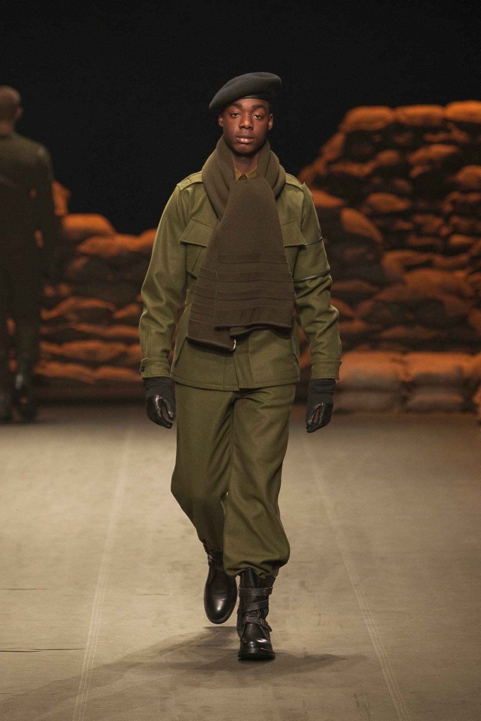 N.Hoolywood Autumn/Winter 2010–11 runway look 5: olive scarf layered over a military jacket and loose trousers with a black beret.