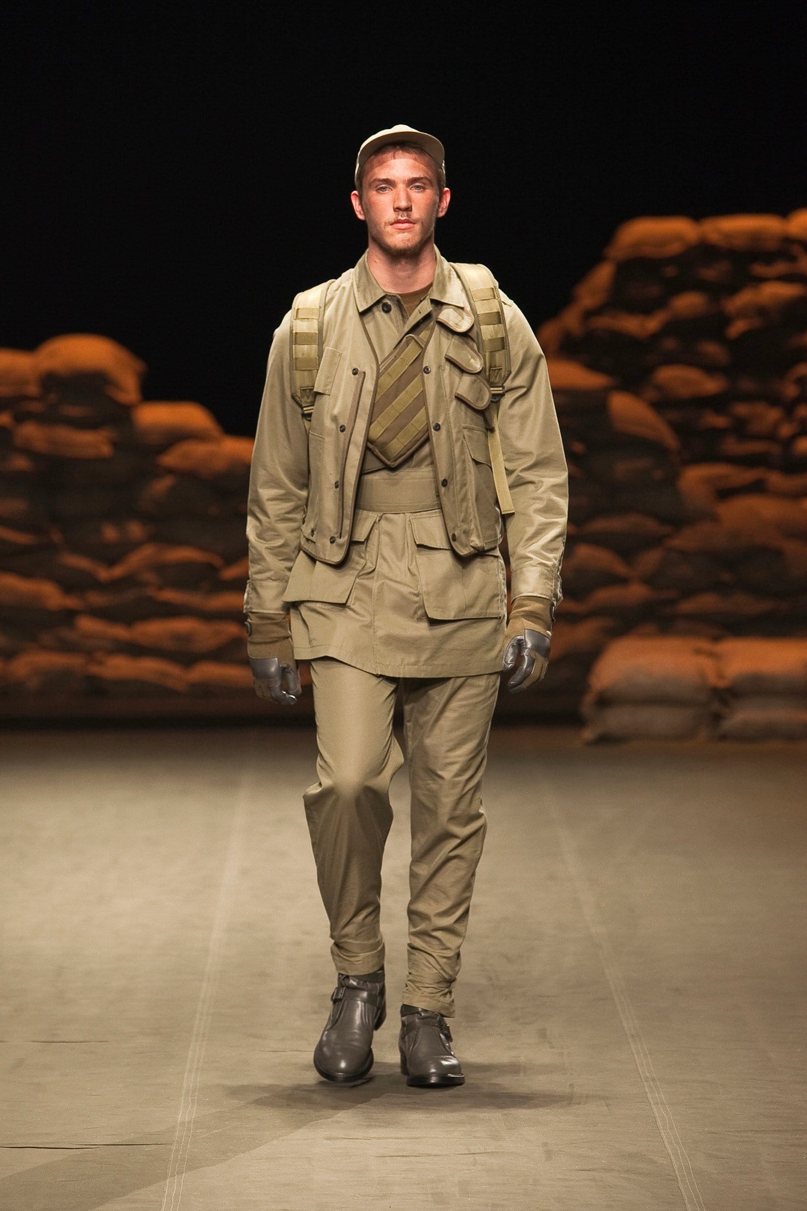 N.Hoolywood Autumn/Winter 2010–11 runway look 7: layered khaki utility jackets with pale trousers, tie, and dark boots.