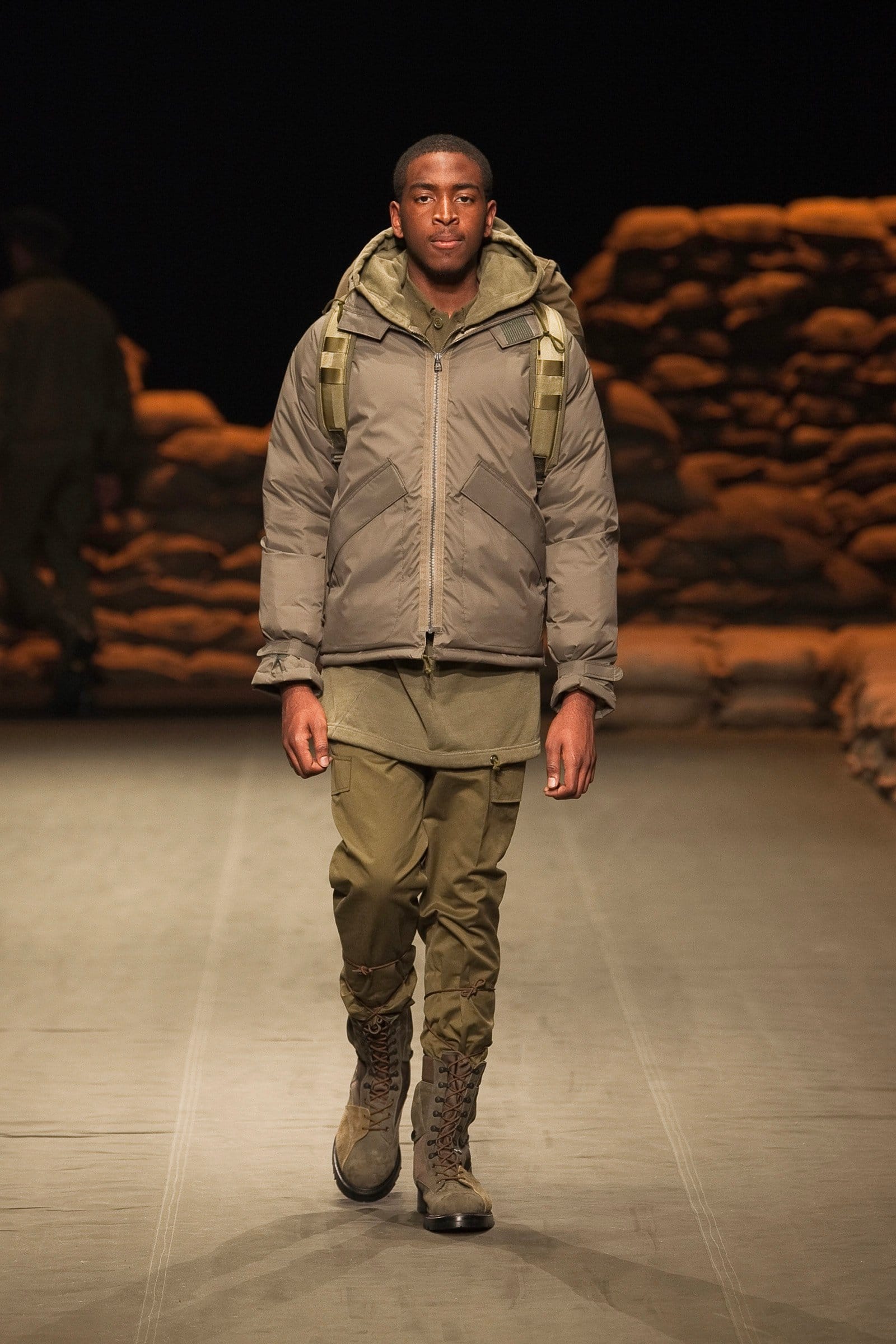 N.Hoolywood Autumn/Winter 2010–11 runway look 15: grey padded hooded jacket with backpack, khaki trousers, and brown combat boots.