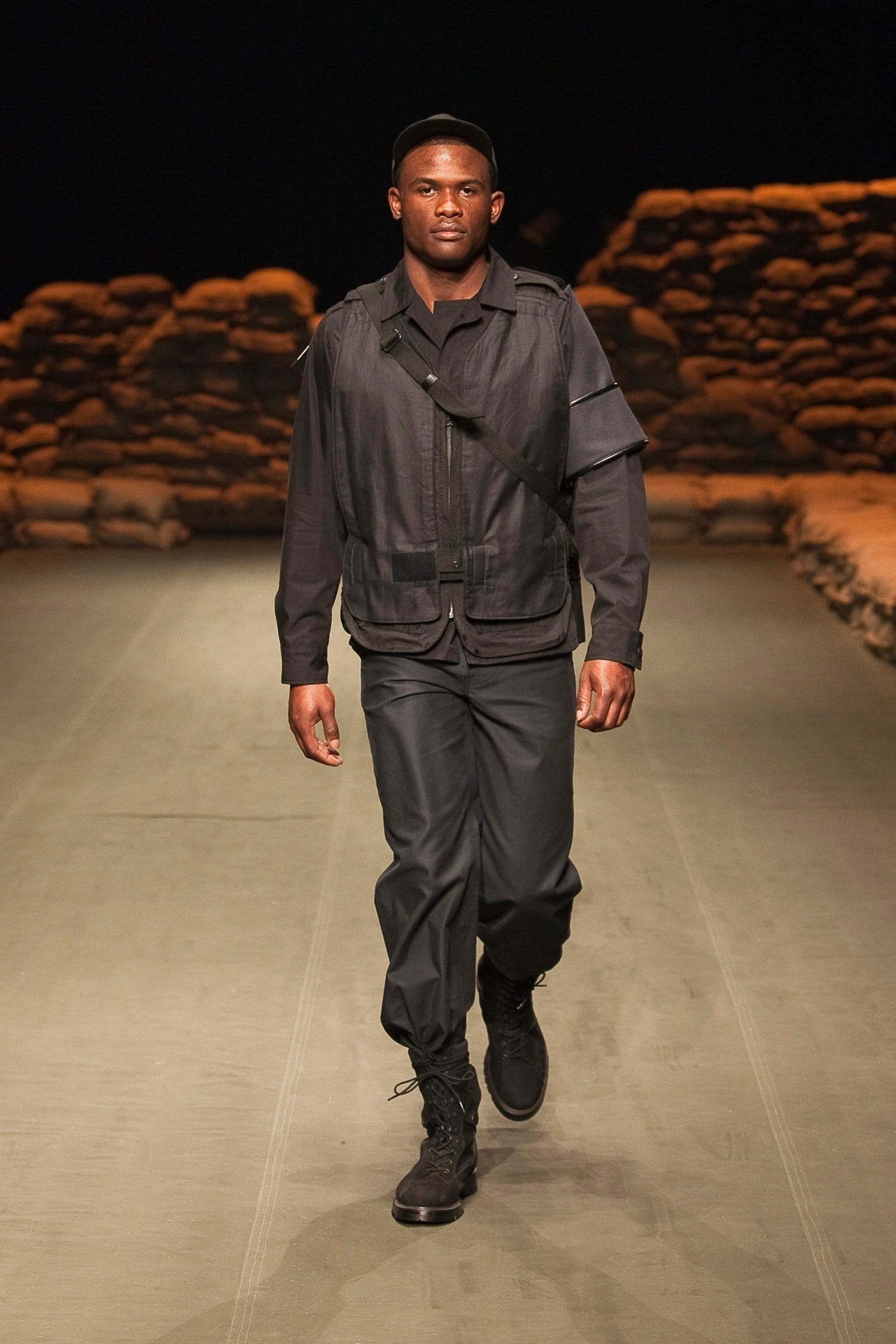 N.Hoolywood Autumn/Winter 2010–11 runway look 17: black cropped military jacket with matching cargo trousers and boots.