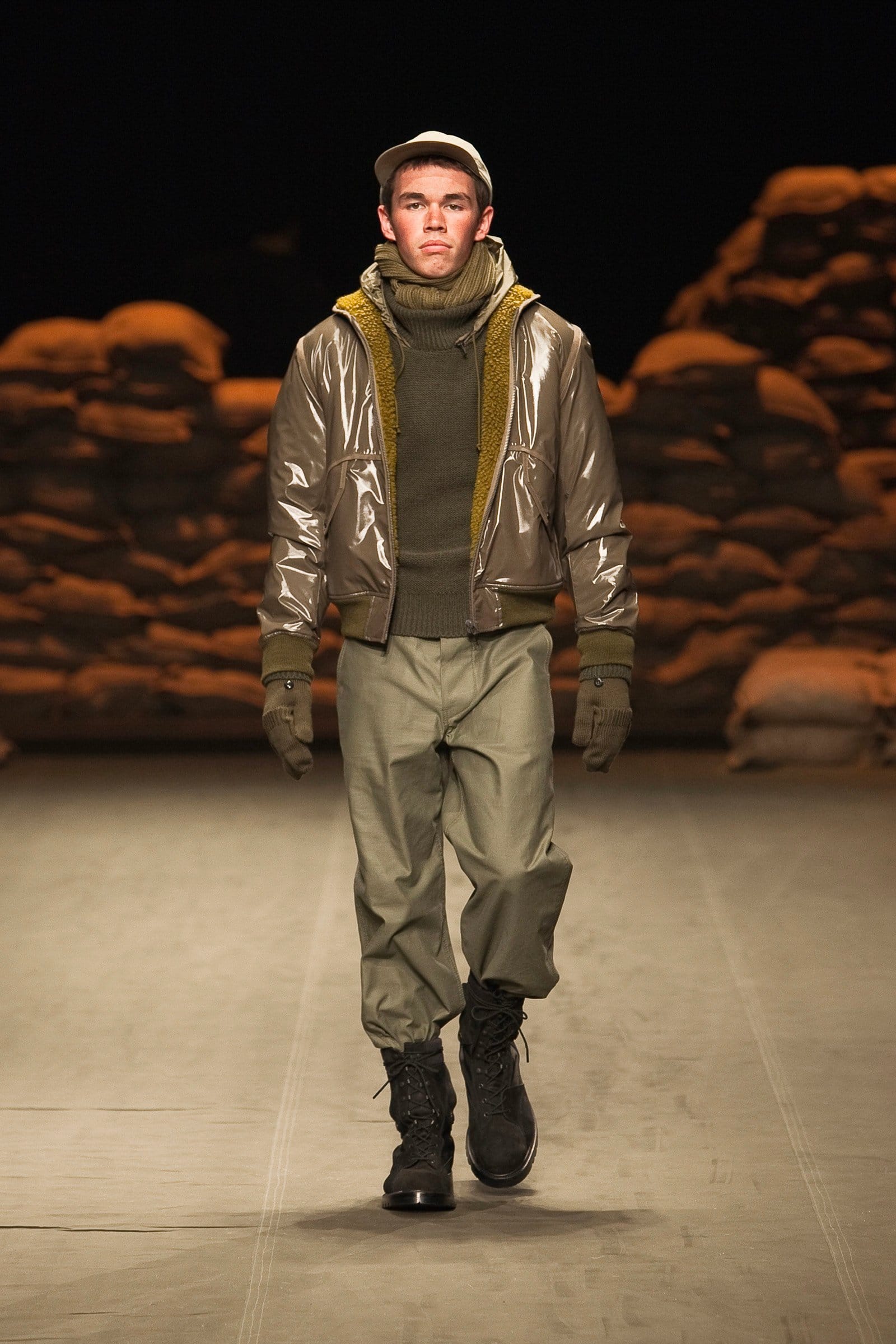 N.Hoolywood Autumn/Winter 2010–11 runway look 19: metallic silver bomber over an olive hooded knit and pale trousers.