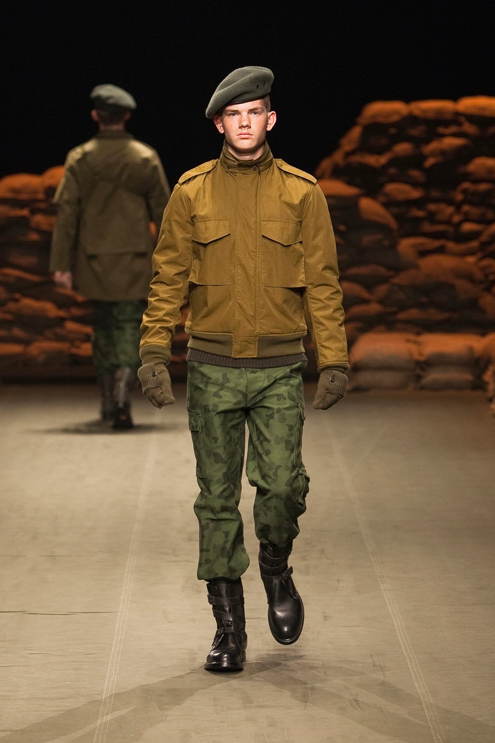 N.Hoolywood Autumn/Winter 2010–11 runway look 28: mustard utility jacket with green camouflage trousers, gloves, and beret.
