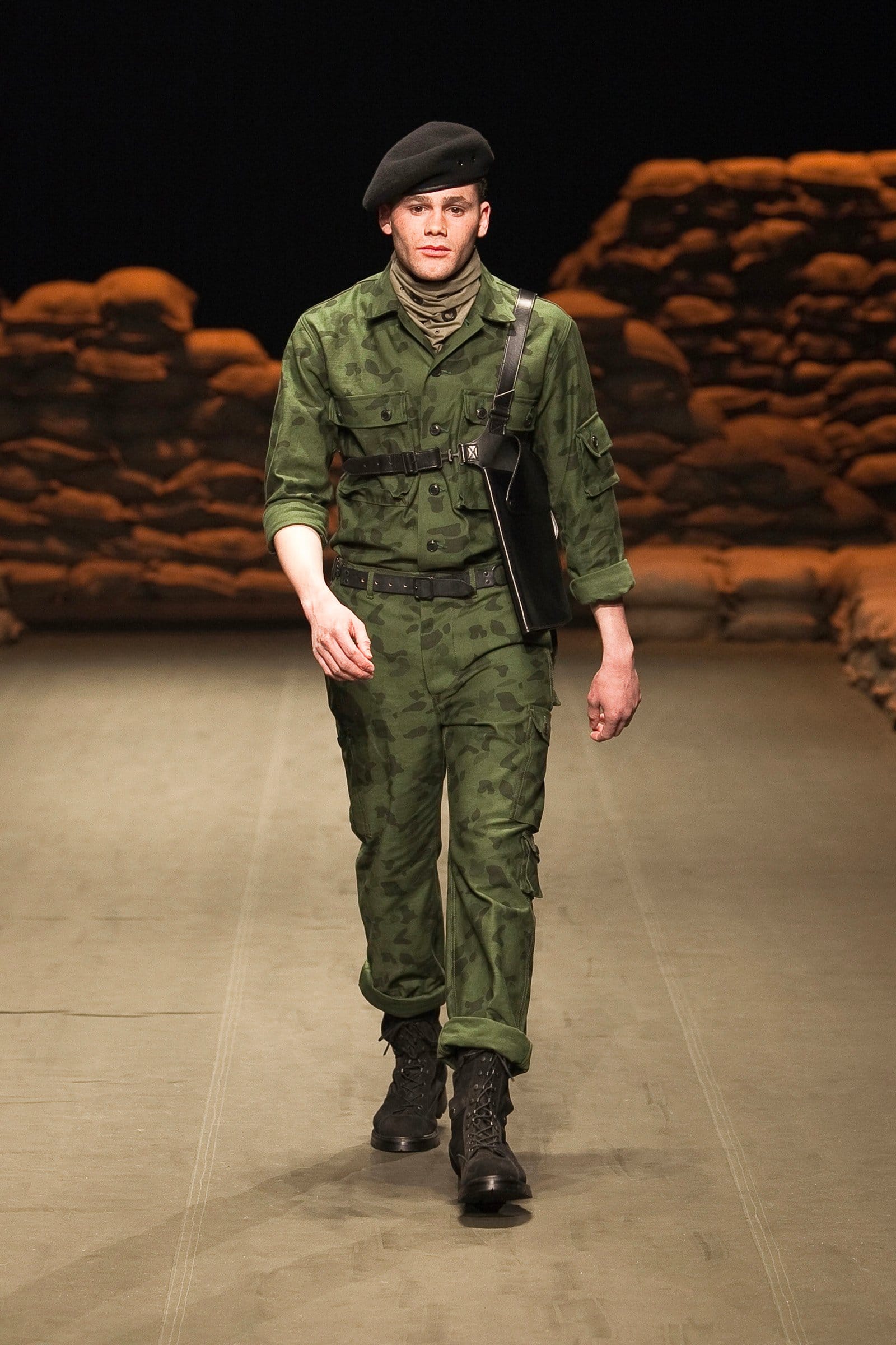 N.Hoolywood Autumn/Winter 2010–11 runway look 30: green camouflage belted field suit with black beret and boots.