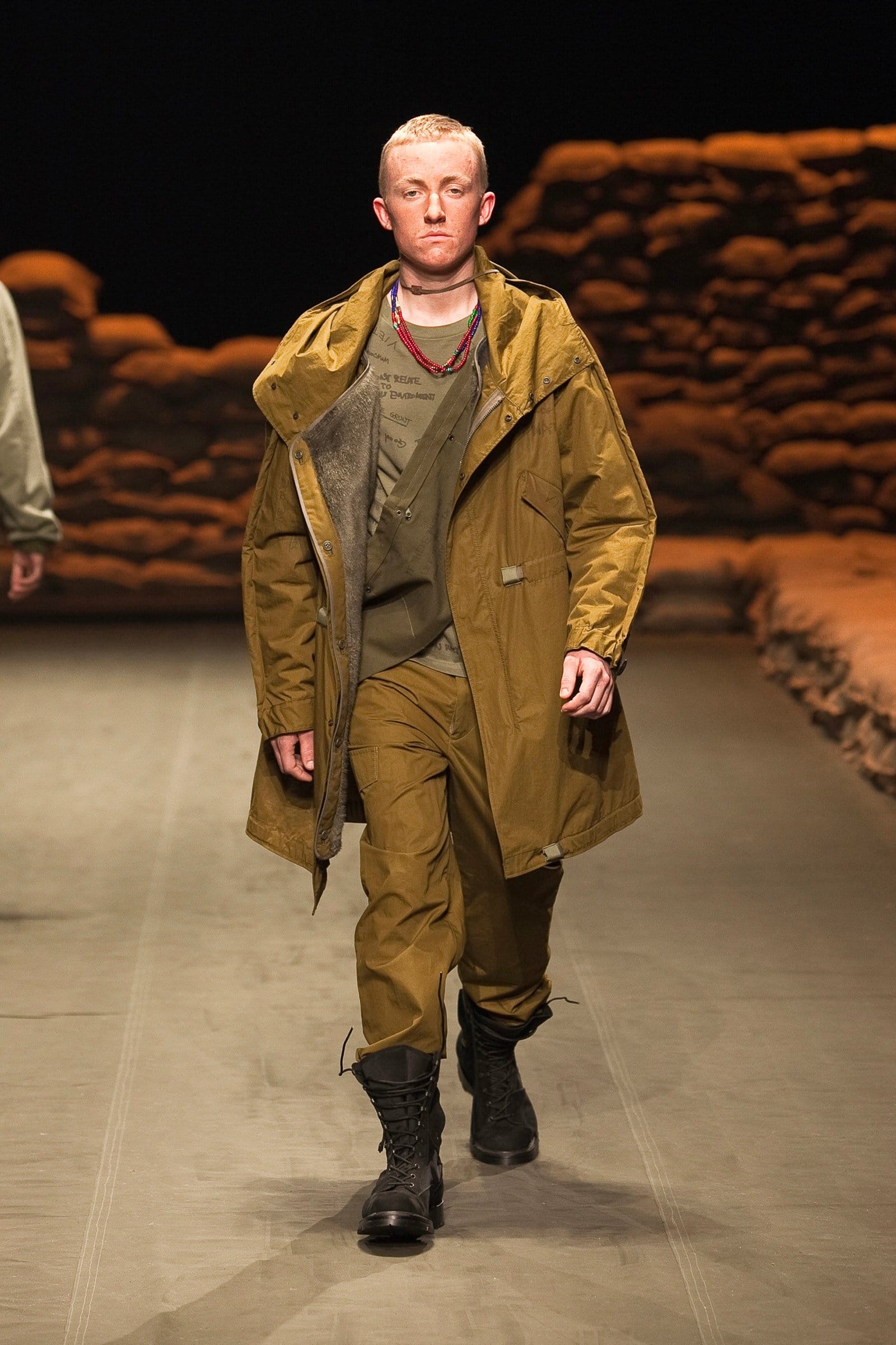 N.Hoolywood Autumn/Winter 2010–11 runway look 37: mustard long military coat over olive layers and matching trousers.