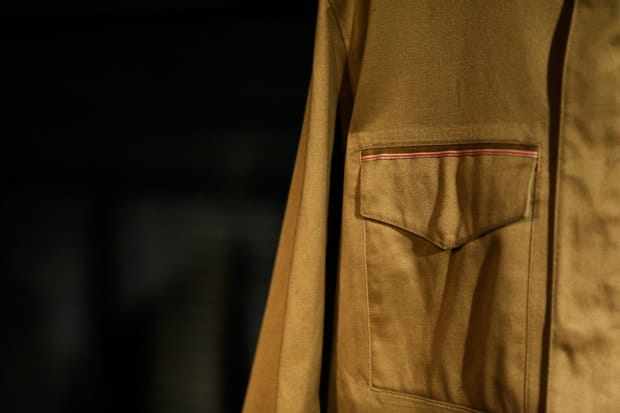 Flap pocket on the tan Nike Sportswear NSW jacket, with red-striped trim above the pocket.