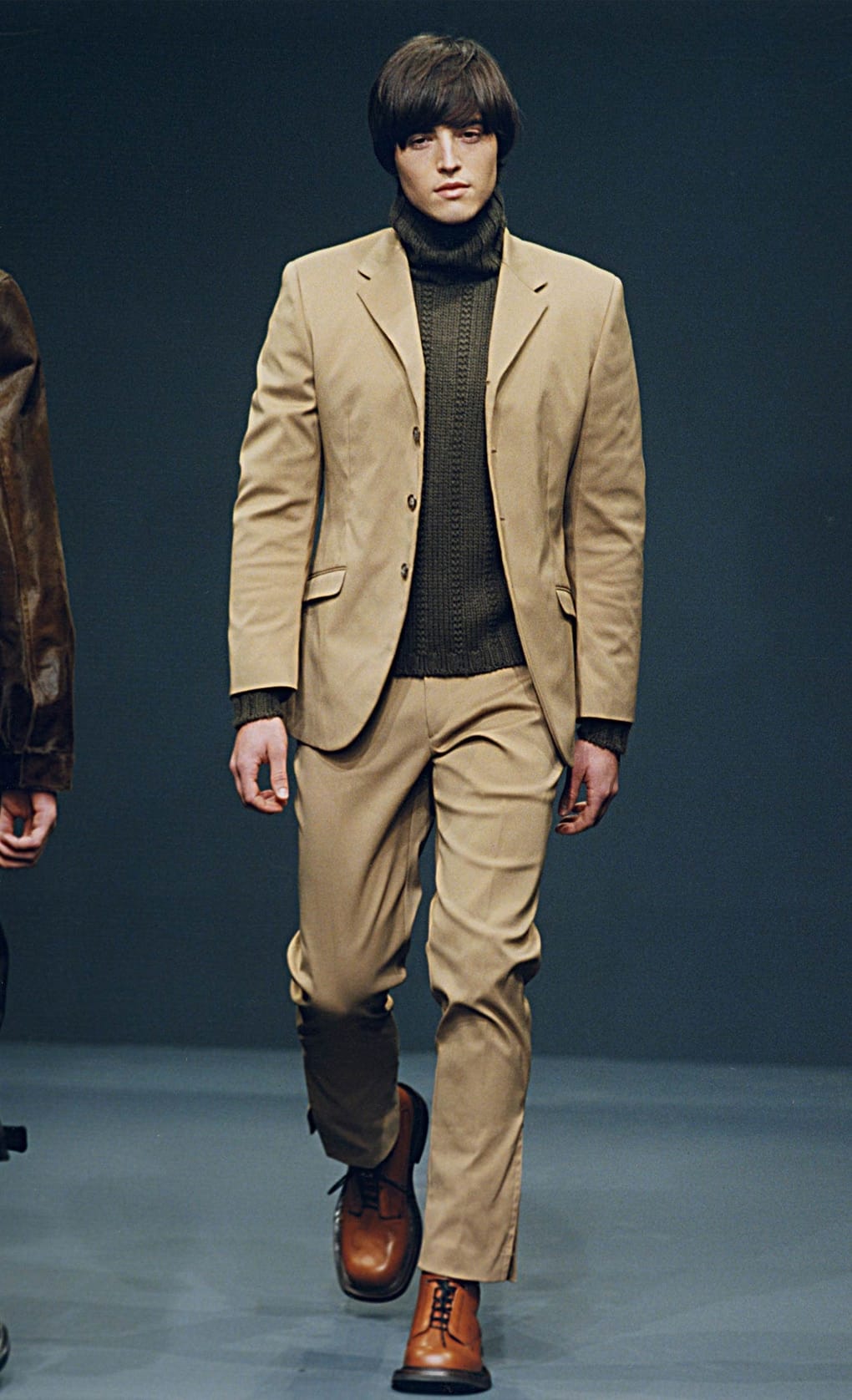Prada Fall/Winter 1999 menswear runway look 10: camel suit layered over a dark turtleneck with two-tone boots.