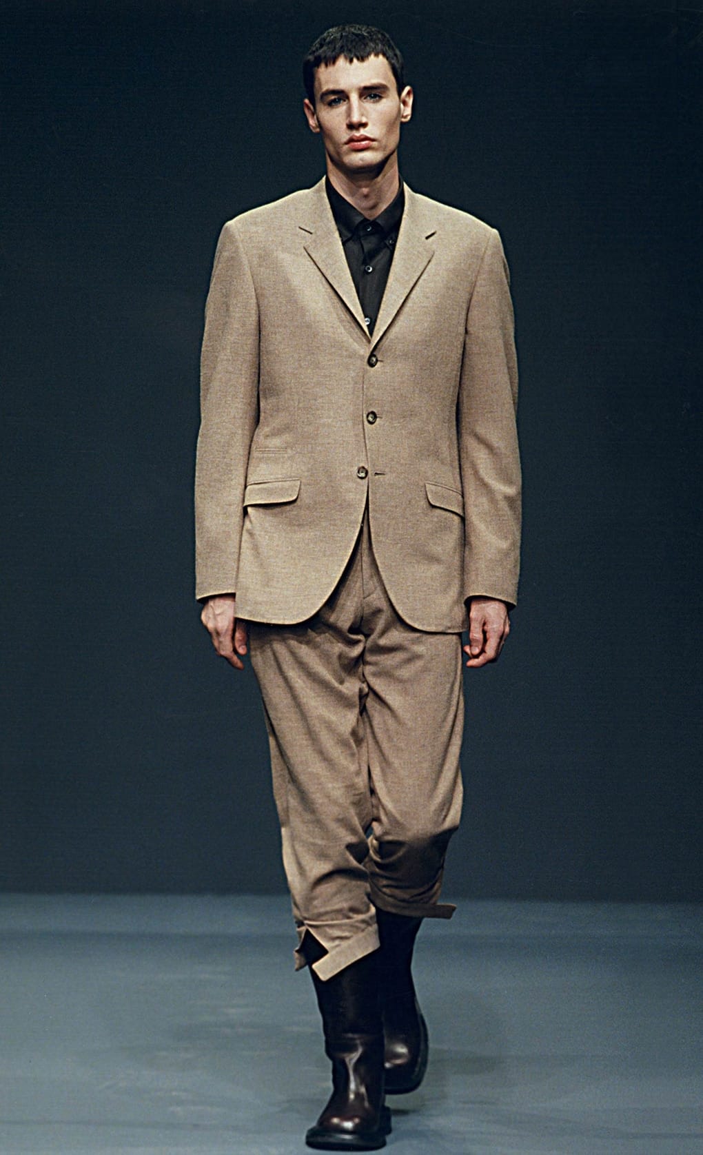 Prada Fall/Winter 1999 menswear runway look 12: beige blazer with loose trousers and tall black boots.