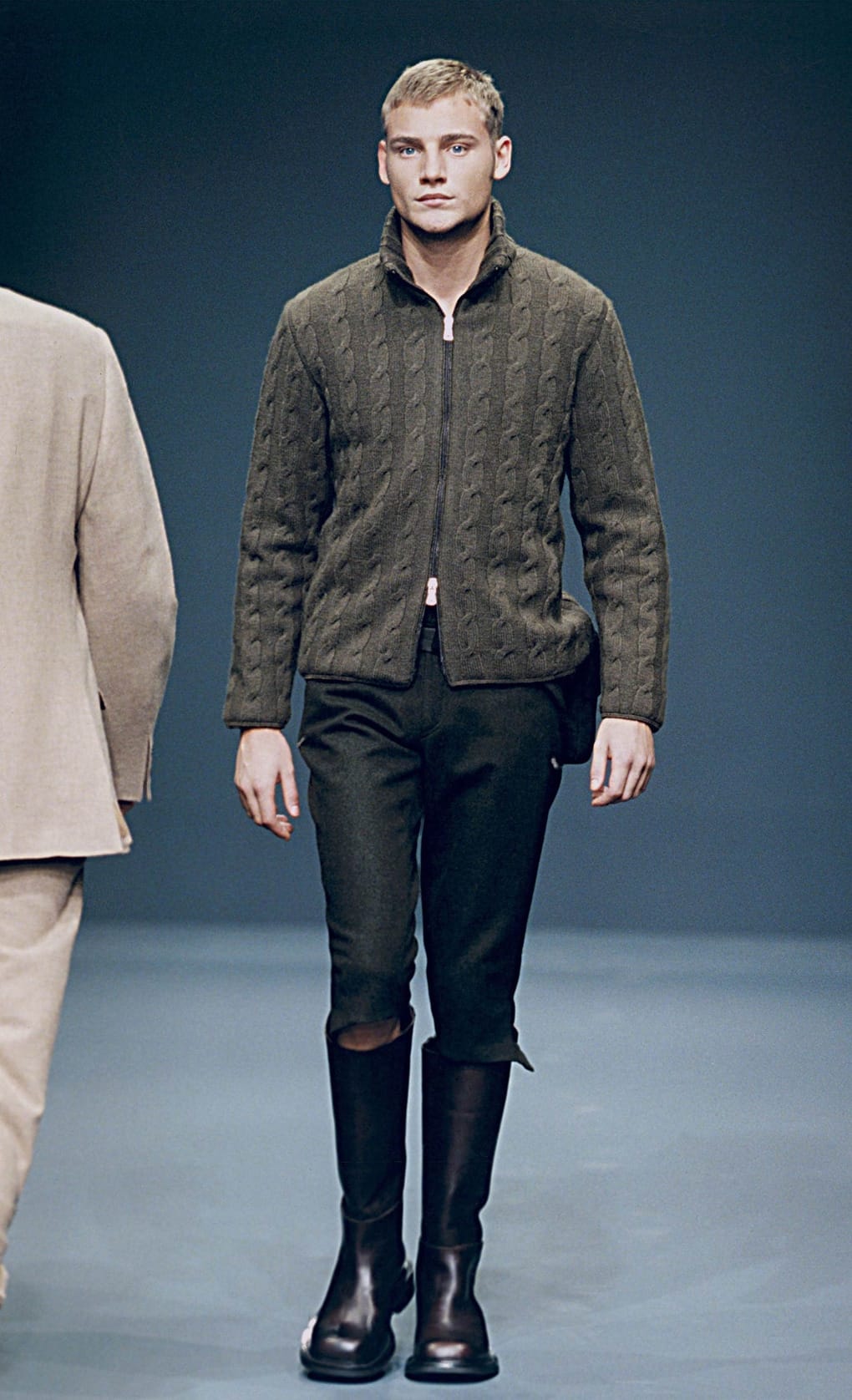 Prada Fall/Winter 1999 menswear runway look 13: dark quilted jacket with black cropped trousers and tall boots.