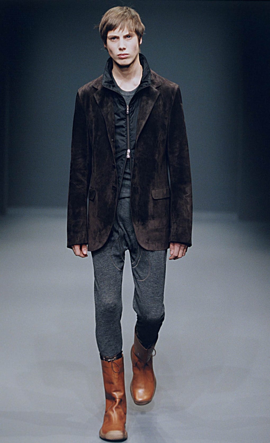 Prada Fall/Winter 1999 menswear runway look 2: dark brown suede jacket with grey cropped trousers and tan boots.