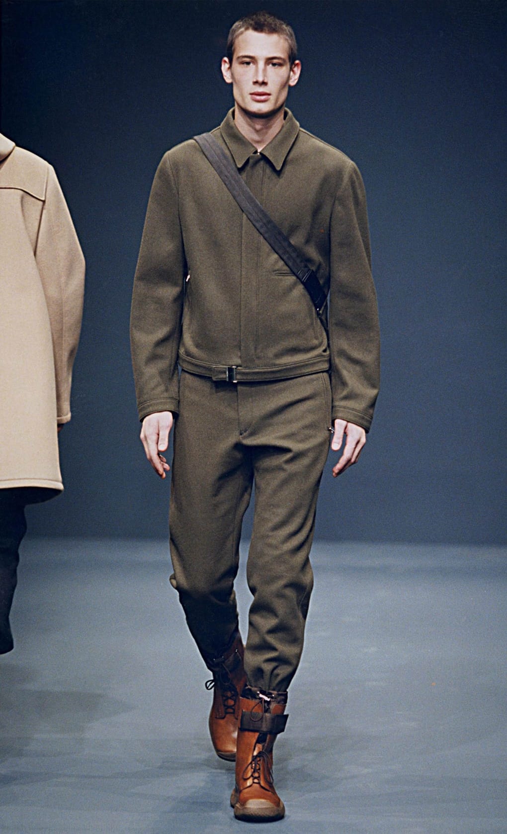 Prada Fall/Winter 1999 menswear runway look 20: olive collared knit top and trousers with a black crossbody strap.