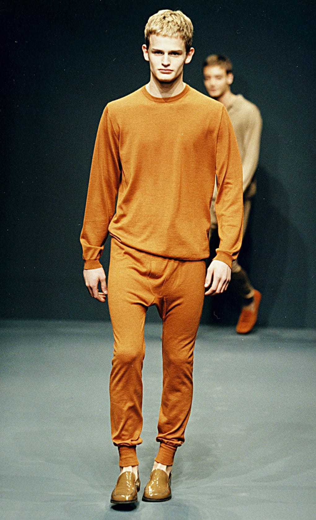 Prada Fall/Winter 1999 menswear runway look 23: orange crewneck top and matching trousers with tan shoes.