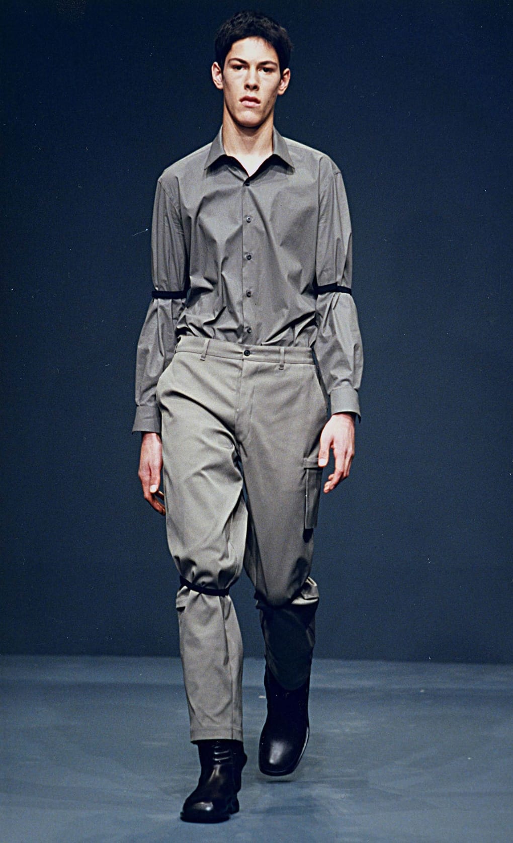 Prada Fall/Winter 1999 menswear runway look 28: grey belted shirt with matching trousers and black boots.