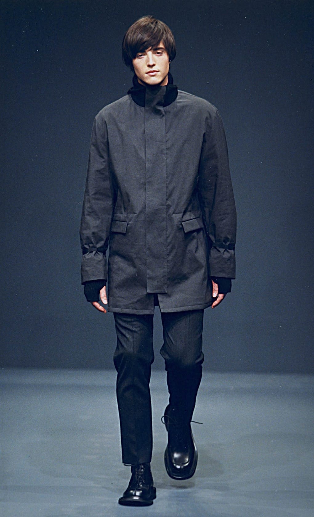 Prada Fall/Winter 1999 menswear runway look 29: dark hooded jacket with cropped trousers and black boots.