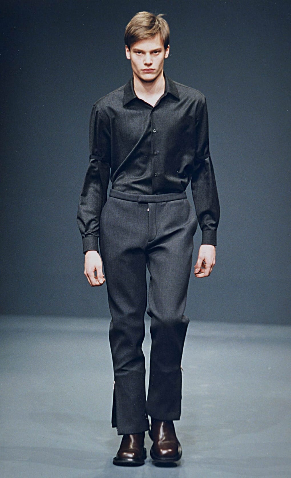 Prada Fall/Winter 1999 menswear runway look 31: black shirt tucked into dark cropped trousers with brown shoes.