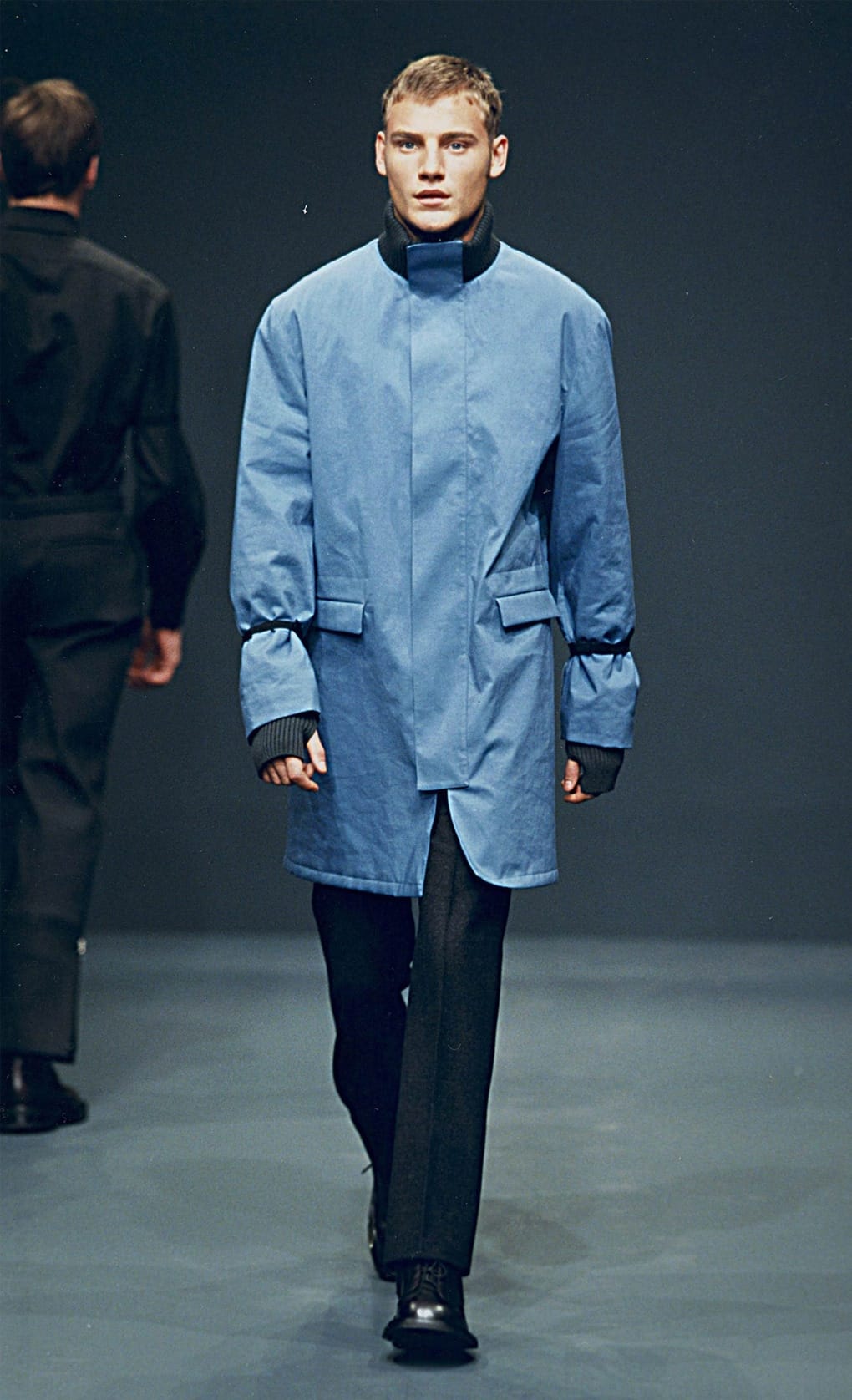 Prada Fall/Winter 1999 menswear runway look 32: pale blue technical coat over black trousers.