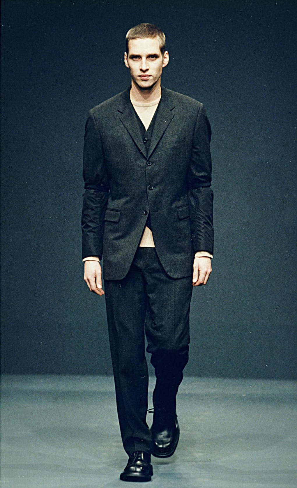 Prada Fall/Winter 1999 menswear runway look 34: black blazer and trousers worn over a bare torso.