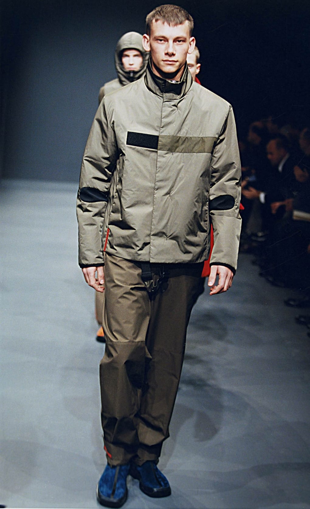 Prada Fall/Winter 1999 menswear runway look 39: grey technical jacket and trousers with blue shoes.