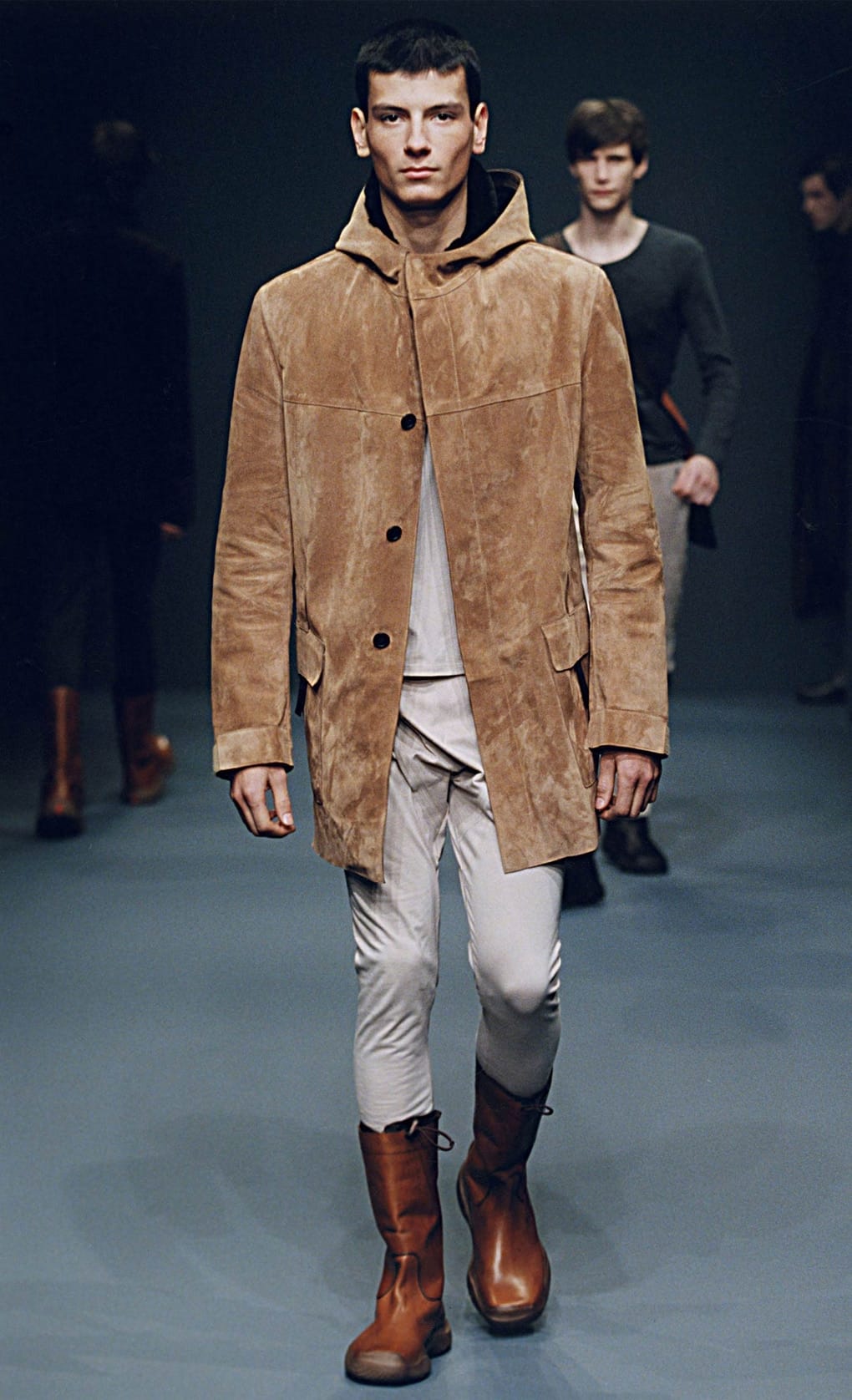 Prada Fall/Winter 1999 menswear runway look 4: tan suede hooded coat with pale trousers and brown boots.
