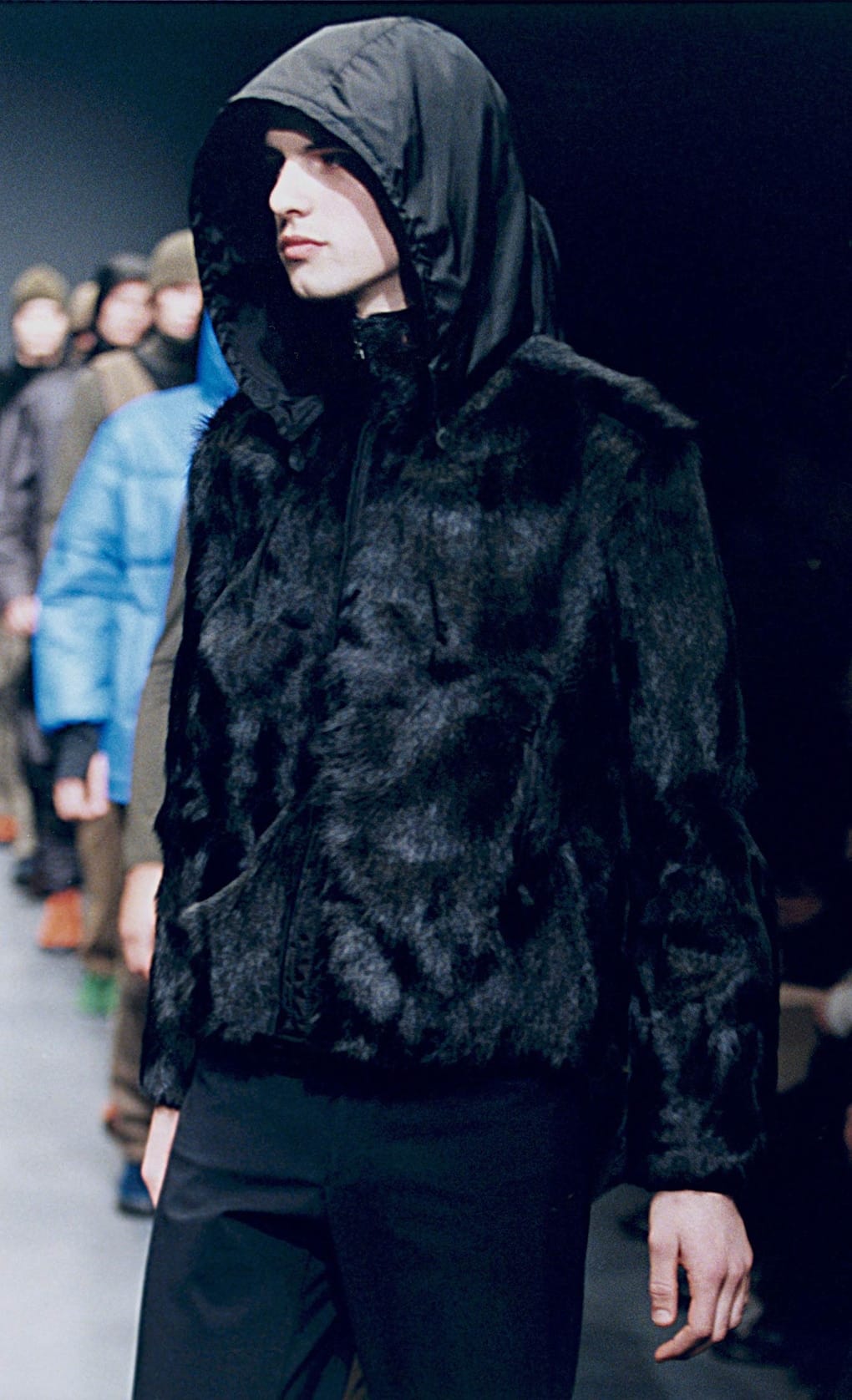 Prada Fall/Winter 1999 menswear runway look 47: black fur hooded top with dark trousers.