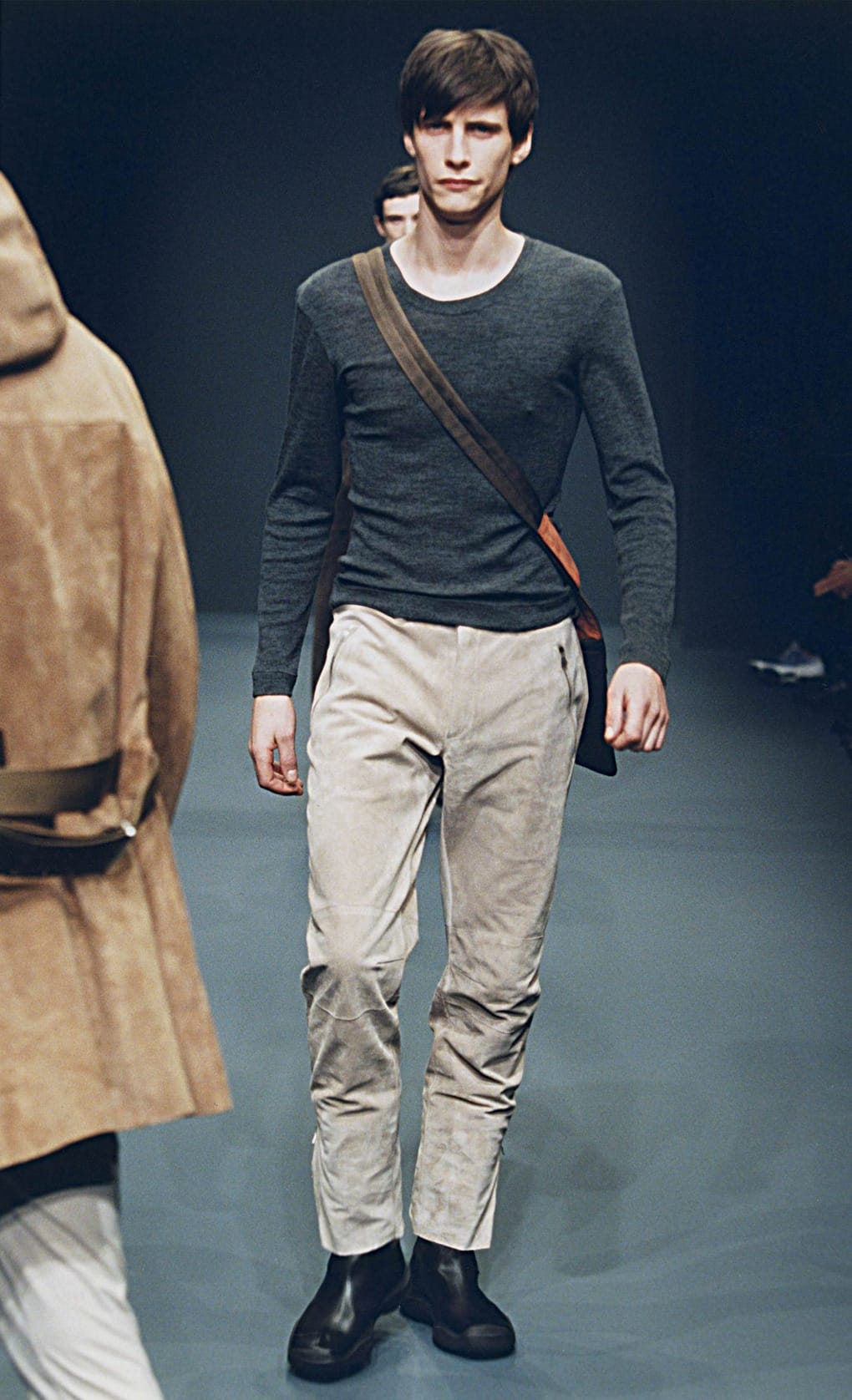 Prada Fall/Winter 1999 menswear runway look 5: charcoal knit top with pale cropped trousers and crossbody bag.