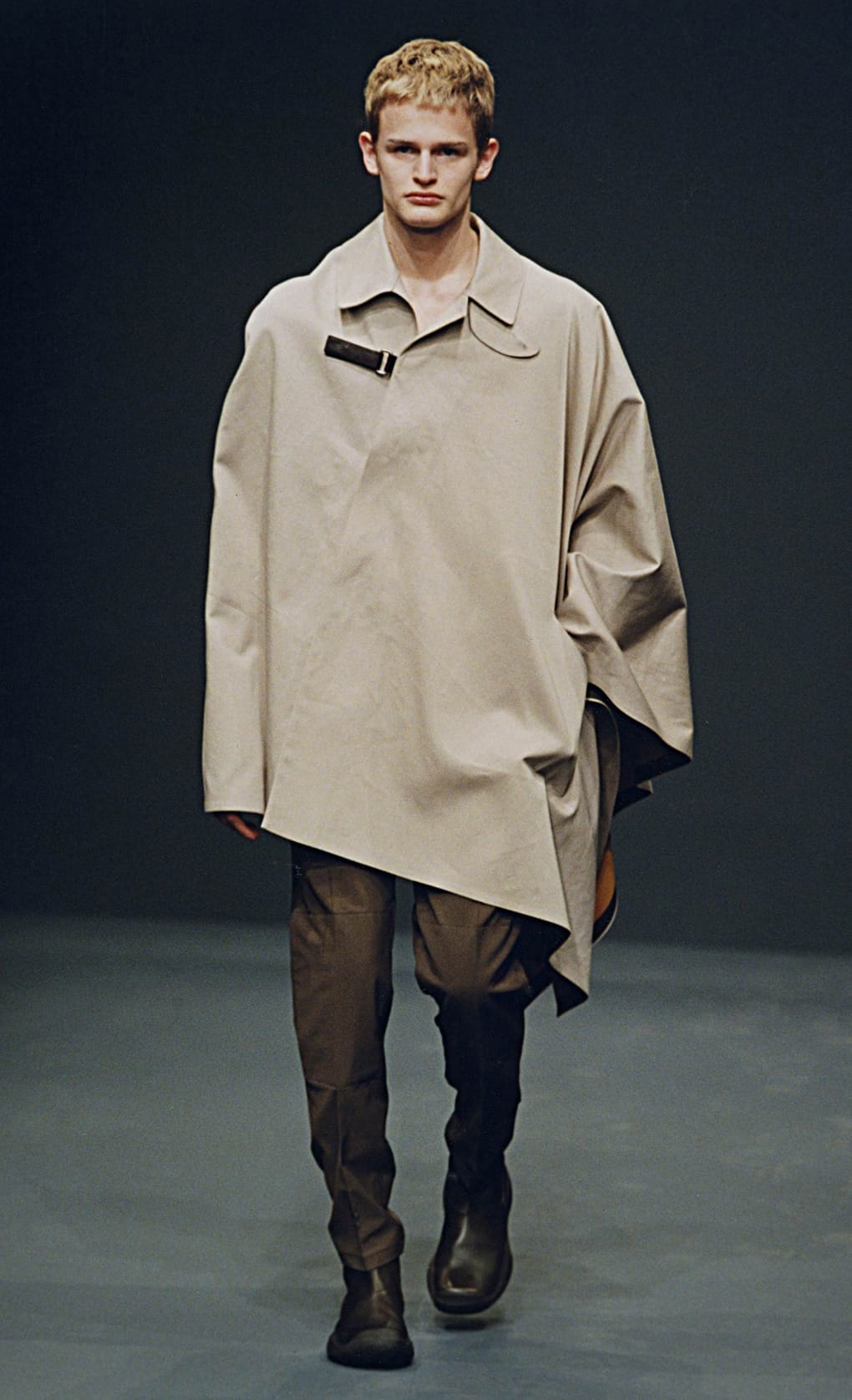 Prada Fall/Winter 1999 menswear runway look 56: oversized pale taupe cape coat with brown trousers.