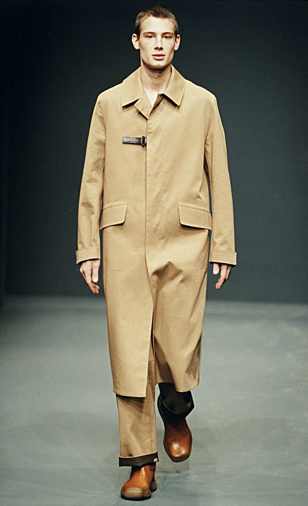 Prada Fall/Winter 1999 menswear runway look 62: long camel coat with matching trousers and two-tone boots.