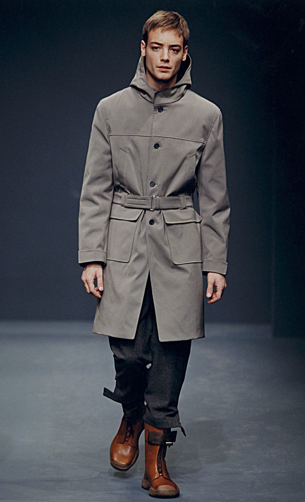 Prada Fall/Winter 1999 menswear runway look 68: grey belted coat with dark cropped trousers and two-tone boots.