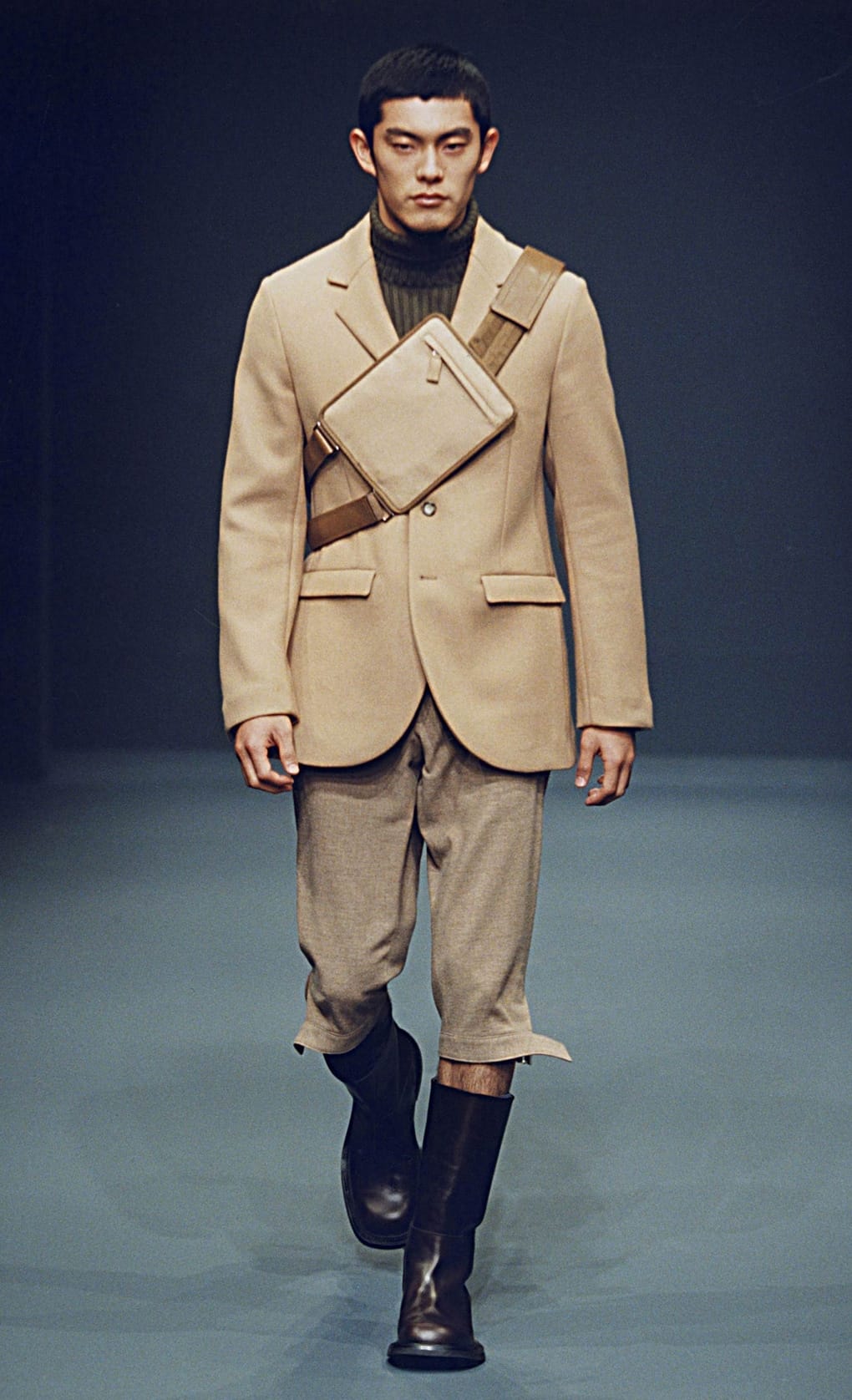 Prada Fall/Winter 1999 menswear runway look 7: camel blazer with cropped trousers, chest bag, and tall black boots.