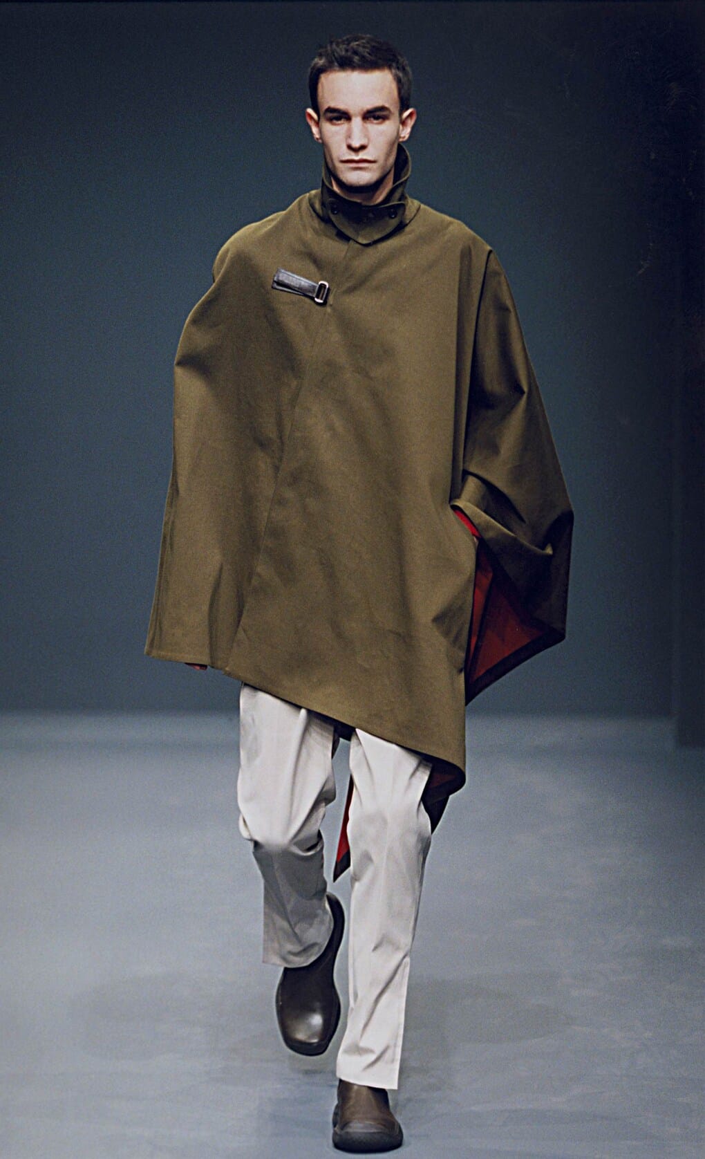 Prada Fall/Winter 1999 menswear runway look 70: olive cape over pale trousers and black boots.