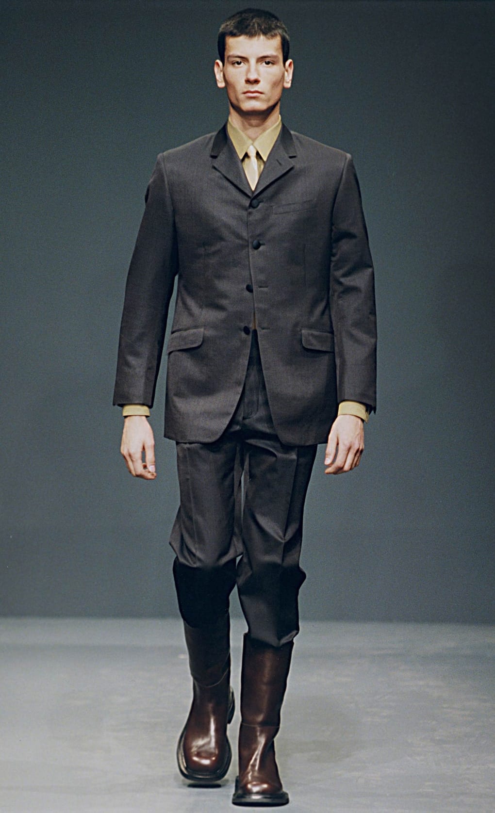 Prada Fall/Winter 1999 menswear runway look 75: charcoal suit with olive shirt and dark cropped trousers.