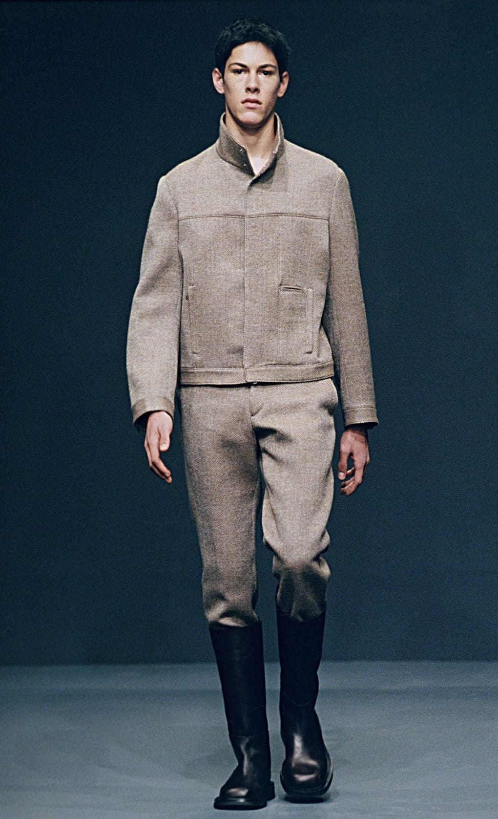 Prada Fall/Winter 1999 menswear runway look 8: pale grey boxy jacket with matching trousers and black boots.